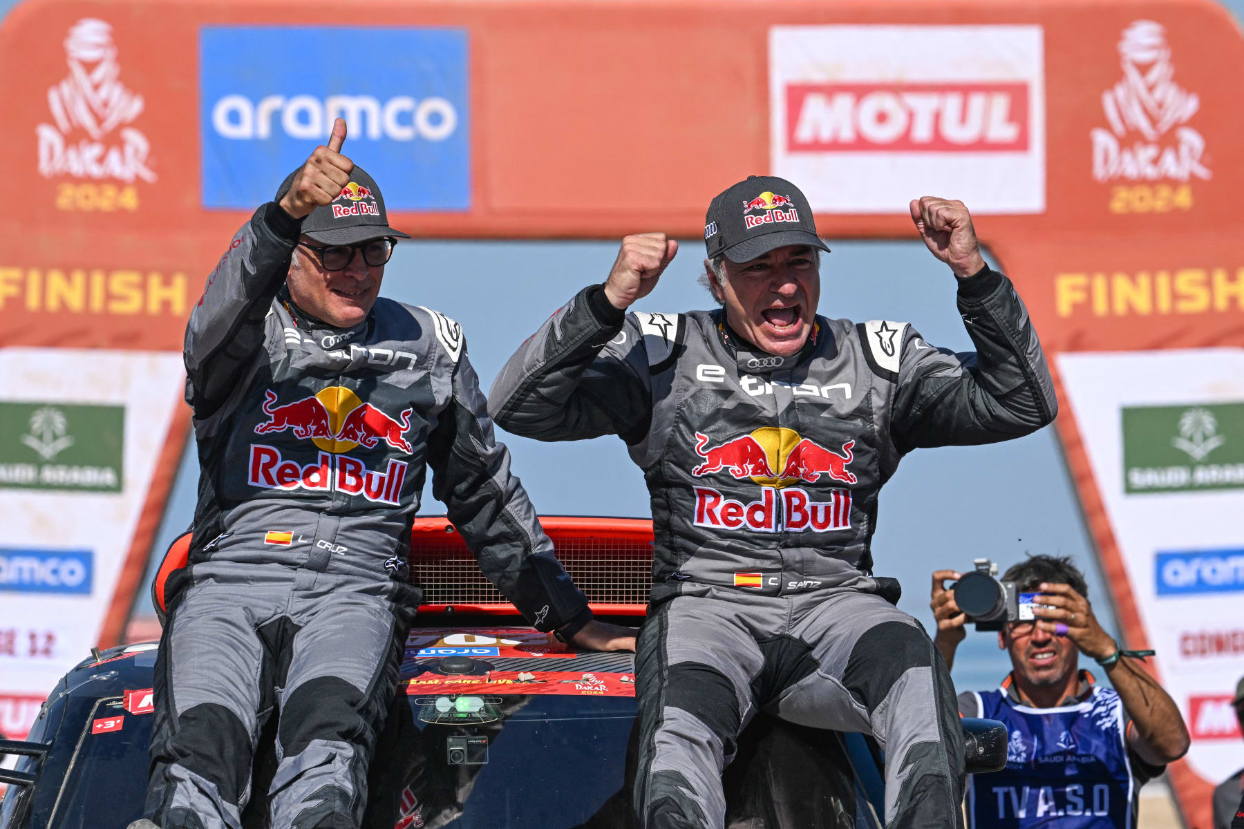 Team Audi Sport's Spanish driver Carlos Sainz (R) and his Spanish co-driver Lucas Cruzof (L) celebrate on their car after crossing the finish line of stage 12  of the Dakar rally 2024 from Yanbu to Yanbu, on January 19, 2024, at the end. Veteran Spanish driver Carlos Sainz won on January 19, 2024 the gruelling Dakar Rally for a fourth time on Friday, becoming at 61 the oldest winner of the race. (Photo by PATRICK HERTZOG / AFP) (Photo by PATRICK HERTZOG/AFP via Getty Images)