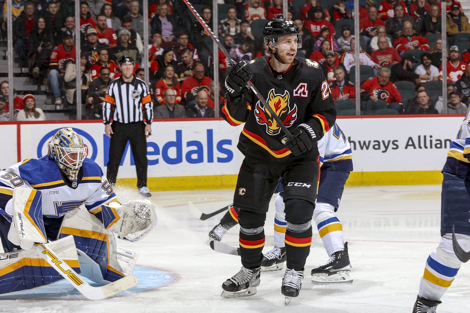 CALGARY, AB - JANUARY 23: Elias Lindholm #28 of the Calgary Flames battles in front of the net against Jordan Binnington #50 of the St Louis Blues at Scotiabank Saddledome on January 23, 2024 in Calgary, Alberta, Canada. (Photo by Gerry Thomas/NHLI via Getty Images)