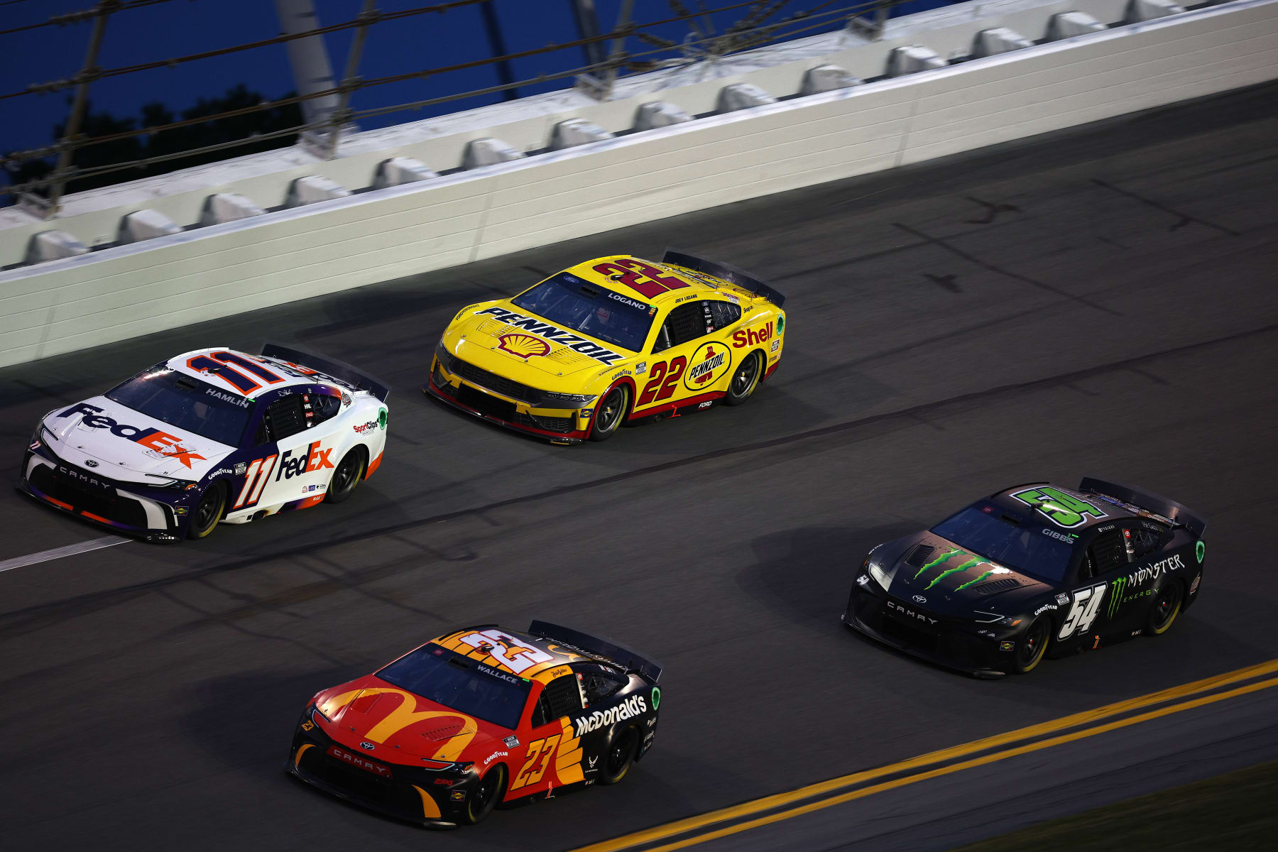 DAYTONA BEACH, FLORIDA - FEBRUARY 16: Bubba Wallace, driver of the #23 McDonald's Toyota, Denny Hamlin, driver of the #11 FedEx Toyota, Joey Logano, driver of the #22 Shell Pennzoil Ford, and Ty Gibbs, driver of the #54 Monster Energy Toyota, drive drives during practice for the NASCAR Cup Series Daytona 500 at Daytona International Speedway on February 16, 2024 in Daytona Beach, Florida. (Photo by Jared C. Tilton/Getty Images)