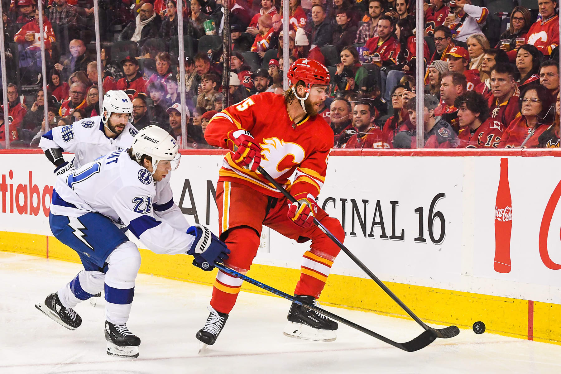 CALGARY, CANADA - DECEMBER 16: Noah Hanifin #55 of the Calgary Flames battles Brayden Point #21 of the Tampa Bay Lightning for the puck during the second period an NHL game at Scotiabank Saddledome on December 16, 2023 in Calgary, Alberta, Canada. (Photo by Derek Leung/Getty Images)