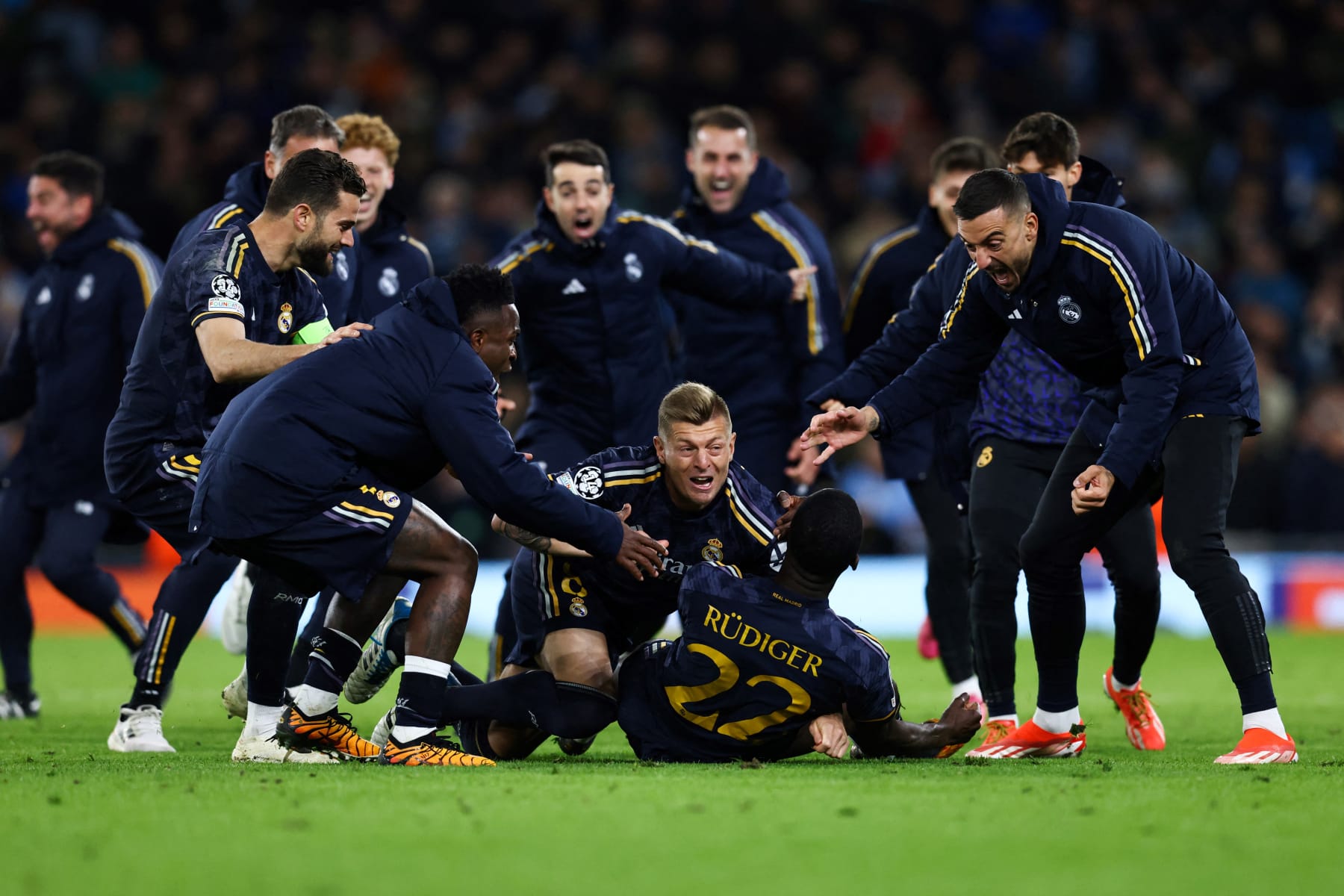 Real Madrid's German defender #22 Antonio Rudiger celebrates with teammates after scoring the winning penalty during the penalty shootout during the UEFA Champions League quarter-final second-leg football match between Manchester City and Real Madrid, at the Etihad Stadium, in Manchester, north-west England, on April 17, 2024. (Photo by Darren Staples / AFP) (Photo by DARREN STAPLES/AFP via Getty Images)