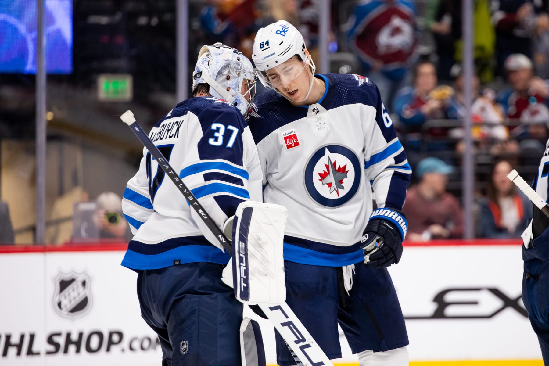 DENVER, COLORADO - APRIL 13: Connor Hellebuyck #37 and Logan Stanley #64 of the Winnipeg Jets hug in celebration after beating the Colorado Avalanche 7-0 at Ball Arena on April 13, 2024 in Denver, Colorado. (Photo by Ashley Potts/NHLI via Getty Images)
