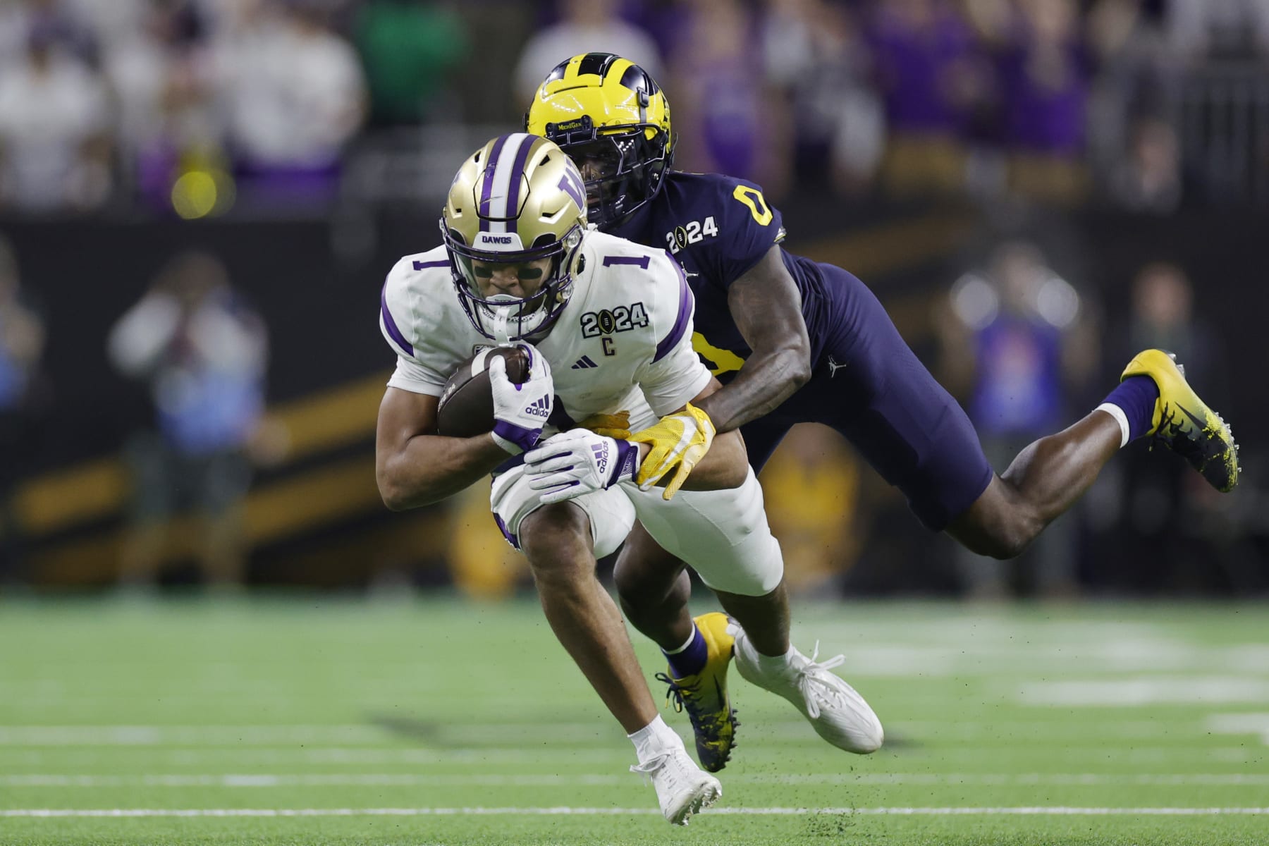 HOUSTON, TEXAS - JANUARY 08: Rome Odunze #1 of the Washington Huskies is tackled by Mike Sainristil #0 of the Michigan Wolverines in the second half during the 2024 CFP National Championship game at NRG Stadium on January 08, 2024 in Houston, Texas. (Photo by Carmen Mandato/Getty Images)