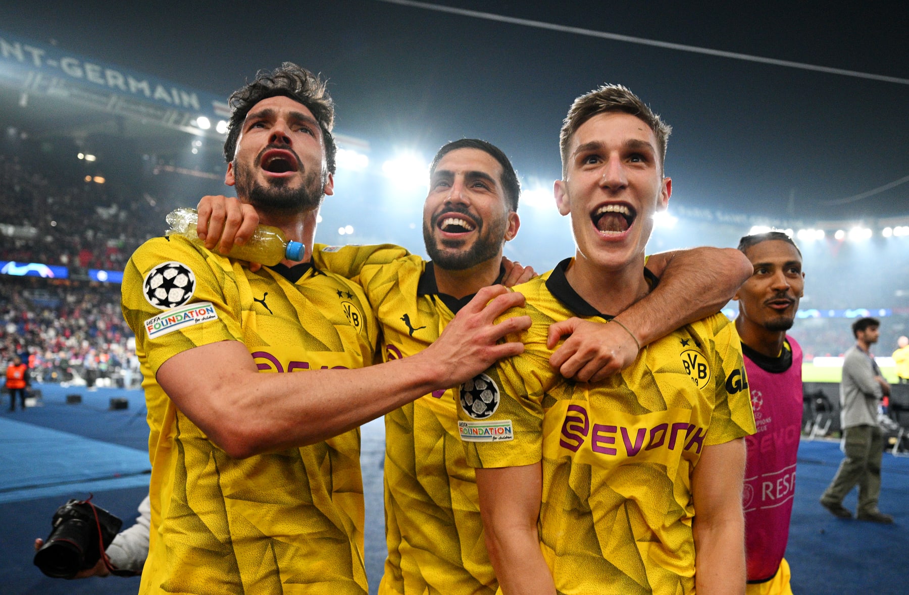 PARIS, FRANCE - MAY 07: Mats Hummels, Emre Can and Nico Schlotterbeck of Borussia Dortmund celebrate victory in front of fans of Borussia Dortmund after defeating Paris Saint-Germain during the UEFA Champions League semi-final second leg match between Paris Saint-Germain and Borussia Dortmund at Parc des Princes on May 07, 2024 in Paris, France. (Photo by Matthias Hangst/Getty Images)