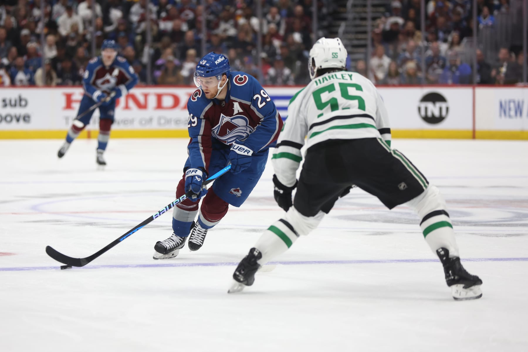 DENVER, COLORADO - MAY 11: Nathan MacKinnon #29 of the Colorado Avalanche skates with the puck against Thomas Harley #55 of the Dallas Stars during the second period in Game Three of the Second Round of the 2024 Stanley Cup Playoffs at Ball Arena on May 11, 2024 in Denver, Colorado.  (Photo by Matthew Stockman/Getty Images)