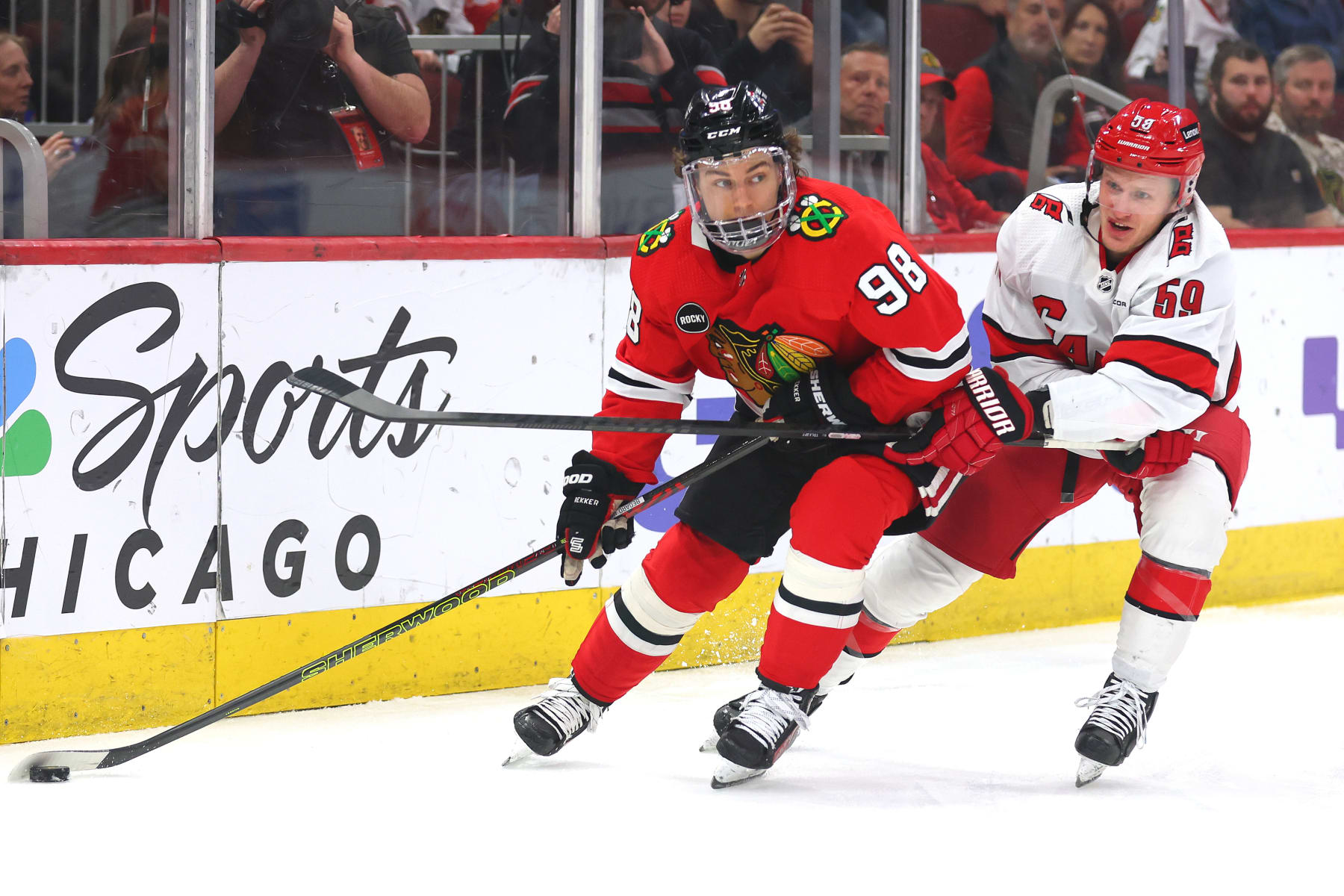 CHICAGO, ILLINOIS - APRIL 14: Connor Bedard #98 of the Chicago Blackhawks and Jake Guentzel #59 of the Carolina Hurricanes battle for control of the puck during the first period at the United Center on April 14, 2024 in Chicago, Illinois. (Photo by Michael Reaves/Getty Images)