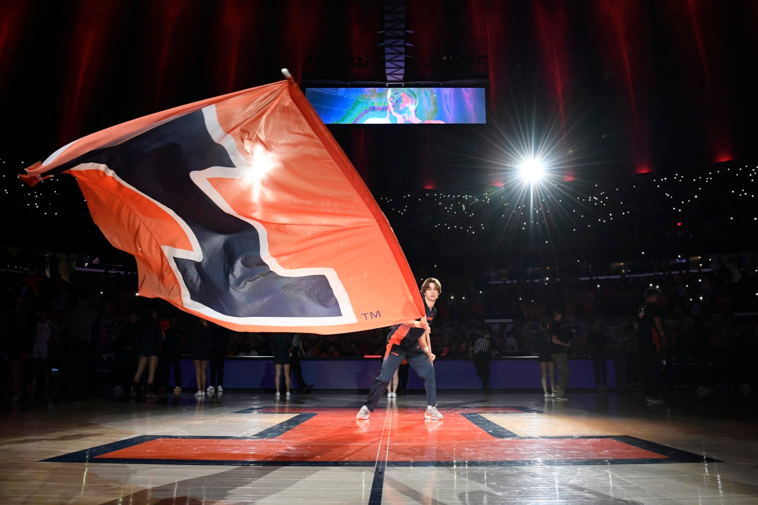 CHAMPAIGN, IL - FEBRUARY 04: A cheerleader waves a flag with an Illinois Fighting Illini logo before the college basketball game between the Nebraska Cornhuskers and the Illinois Fighting Illini on February 4, 2024, at the State Farm Center in Champaign, Illinois. (Photo by Michael Allio/Icon Sportswire via Getty Images) CHAMPAIGN, IL - FEBRUARY 04: A cheerleader waves a flag with an Illinois Fighting Illini logo before the college basketball game between the Nebraska Cornhuskers and the Illinois Fighting Illini on February 4, 2024, at the State Farm Center in Champaign, Illinois. (Photo by Michael Allio/Icon Sportswire via Getty Images)