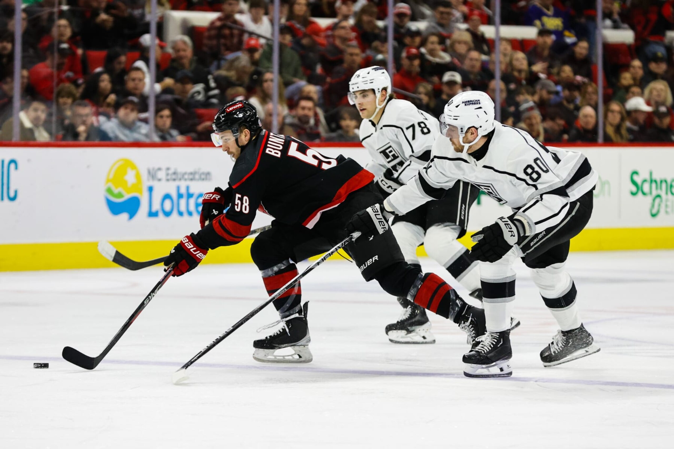 RALEIGH, NC - JANUARY 15: Michael Bunting #58 of the Carolina Hurricanes skates with the puck against Pierre-Luc Dubois #80 of the Los Angeles Kings and Alex Laferriere #78 during the second period of the game at PNC Arena on January 15, 2024 in Raleigh, North Carolina. (Photo by Jaylynn Nash/Getty Images)