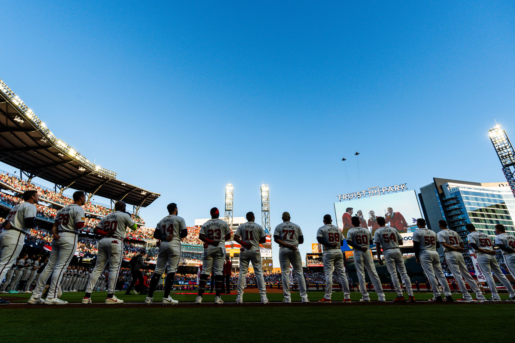 ATLANTA, GA - APRIL 05: Austin Riley #27, Matt Olson #28, Marcell Ozuna #20, Adam Duvall #14, Michael Harris II #23, Orlando Arcia #11, Joe Jiménez #77, Tyler Matzek #68, Jesse Chavez #60, Max Fried #54, Dylan Lee #52, Chris Sale #51, Charlie Morton #50 and Aaron Bummer #49 of the Atlanta Braves stand on the line during the national anthem flyover before the game against the Arizona Diamondbacks at Truist Park on Friday, April 5, 2024 in Atlanta, Georgia. (Matthew Grimes Jr./Atlanta Braves/Getty Images)