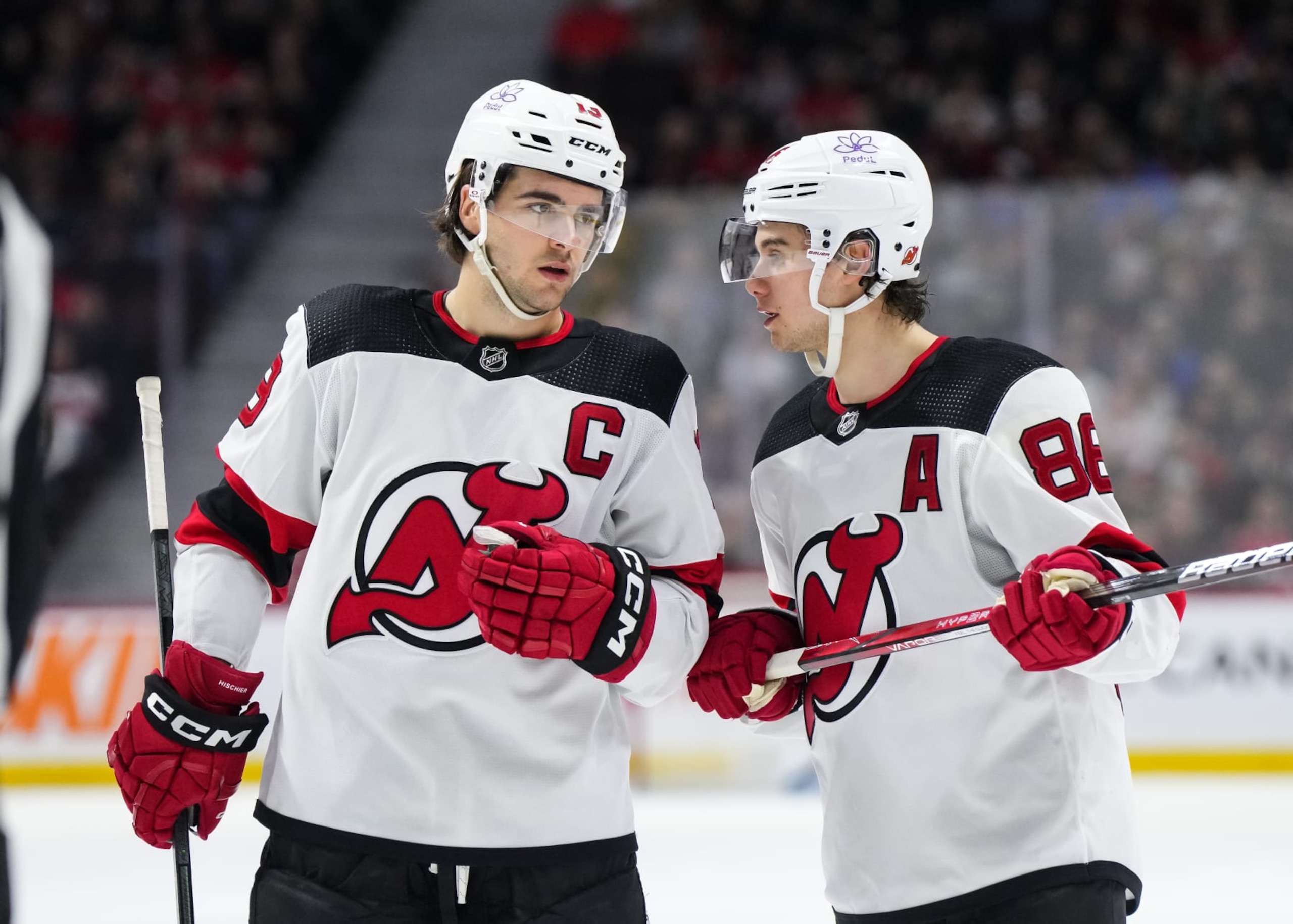OTTAWA, CANADA - APRIL 6:  Nico Hischier #13 of the New Jersey Devils talks with teammate Jack Hughes #86 in a game against the Ottawa Senators at Canadian Tire Centre on April 6, 2024 in Ottawa, Ontario, Canada.  (Photo by Andrea Cardin/NHLI via Getty Images)
