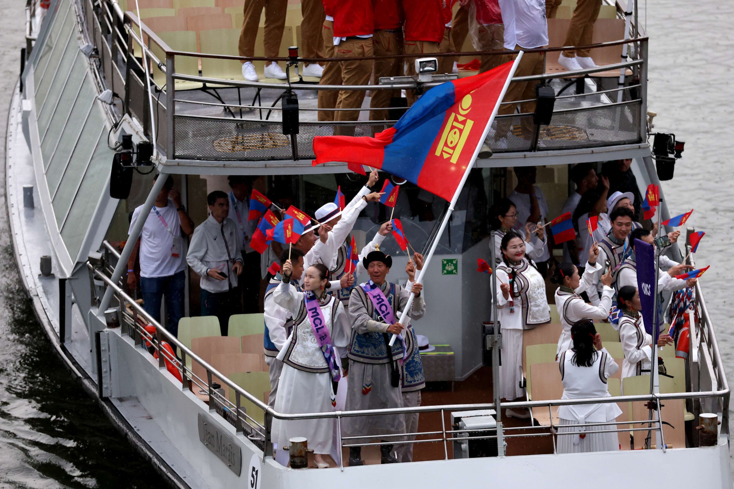 PARIS, FRANCE - JULY 26: Ser-Od Bat-Ochir and Yesugen Oyuntsetseg, Flagbearers of Team Mongolia, are seen waving their flag on a boat along the River Seine  during the opening ceremony of the Olympic Games Paris 2024 on July 26, 2024 in Paris, France. (Photo by Lars Baron/Getty Images)