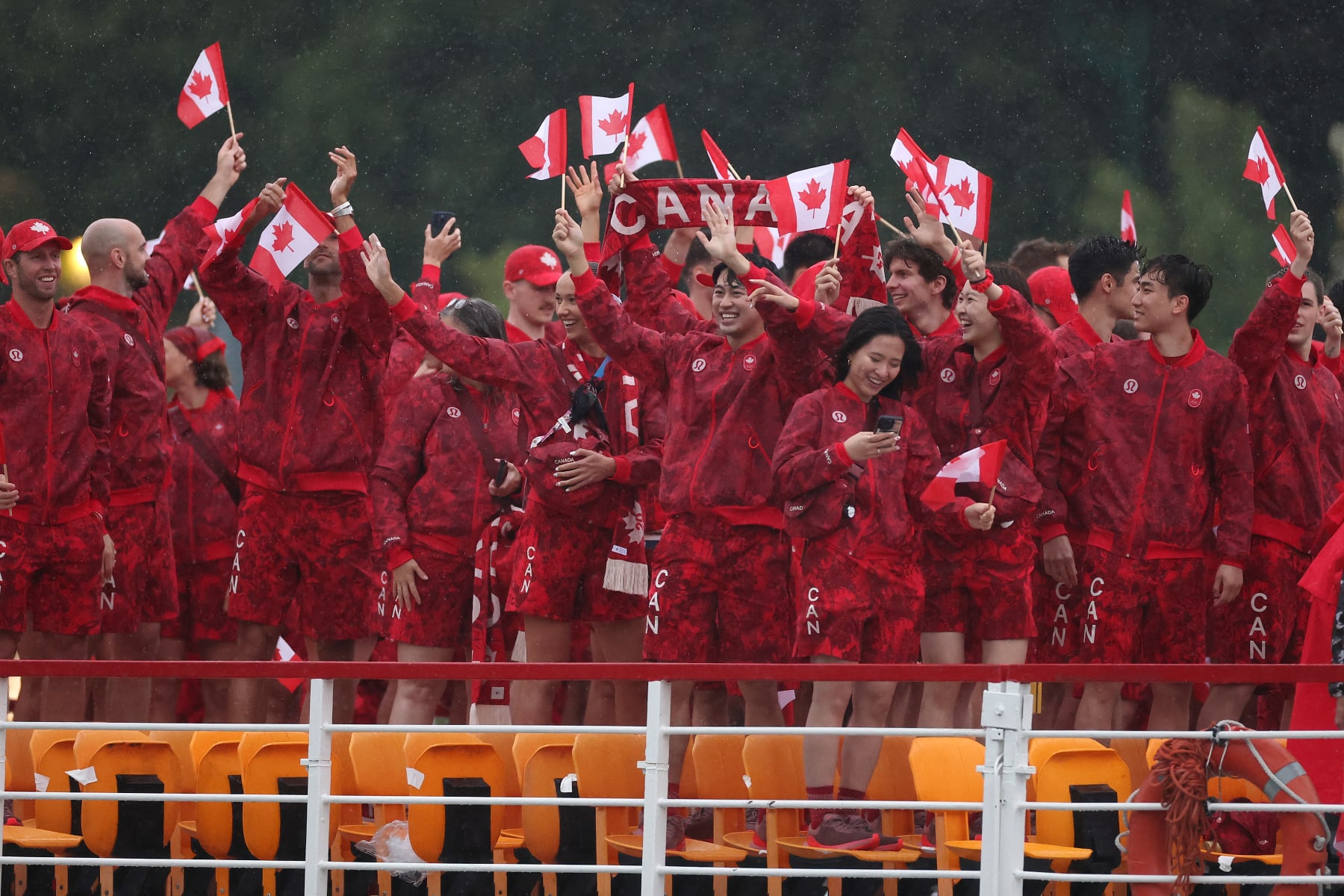 PARIS, FRANCE - JULY 26: Athletes of Team Canada wave their flags on the team boat along the River Seine during the opening ceremony of the Olympic Games Paris 2024 on July 26, 2024 in Paris, France. (Photo by Steph Chambers / POOL / AFP) (Photo by STEPH CHAMBERS/POOL/AFP via Getty Images)