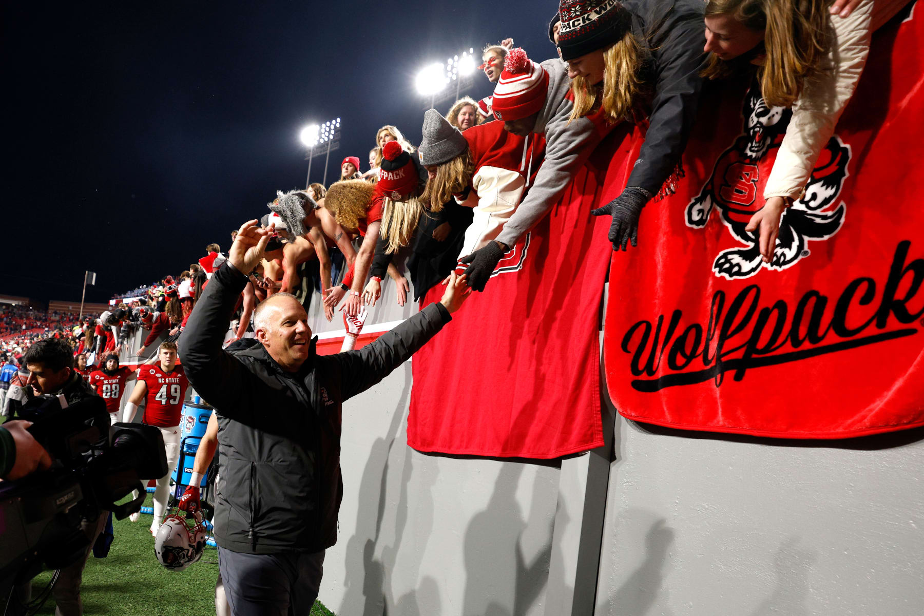 RALEIGH, NORTH CAROLINA - NOVEMBER 25: Head coach Dave Doeren of the NC State Wolfpack celebrates with fans following their 39-20 win against the North Carolina Tar Heels at Carter-Finley Stadium on November 25, 2023 in Raleigh, North Carolina. (Photo by Lance King/Getty Images)