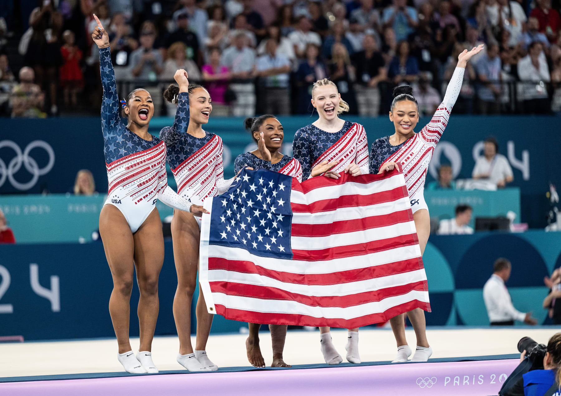 PARIS, FRANCE - JULY 30: Jordan Chiles, Hezly Rivera, Simone Biles, Jade Carey, Sunisa Lee of USA celebrate victory while the women´s team final with the USA flag  on day four of the Olympic Games Paris 2024 at Bercy Arena on July 30, 2024 in Paris, France. (Photo by Markus Gilliar - GES Sportfoto/Getty Images)