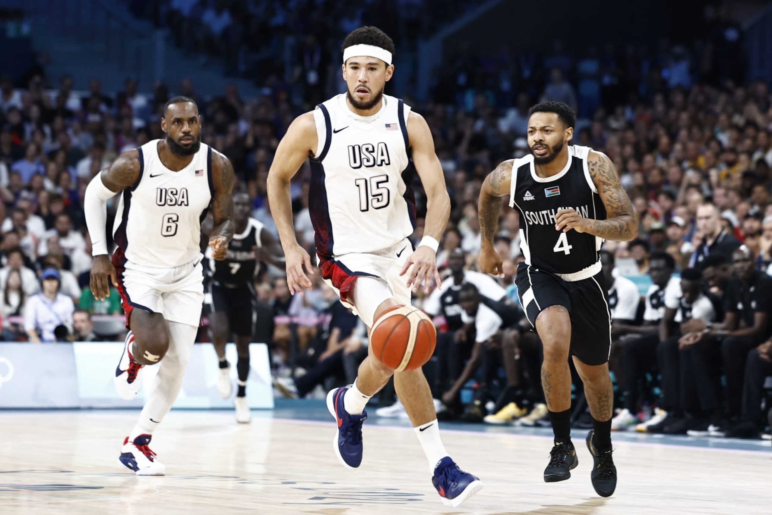 USA's #15 Devin Booker dribbles the ball past South Sudan's #04 Carlik Jones (R) in the men's preliminary round group C basketball match between USA and South Sudan during the Paris 2024 Olympic Games at the Pierre-Mauroy stadium in Villeneuve-d'Ascq, northern France, on July 31, 2024. (Photo by Sameer Al-Doumy / AFP) (Photo by SAMEER AL-DOUMY/AFP via Getty Images)