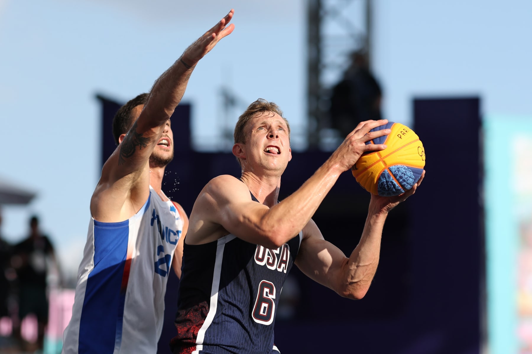 PARIS, FRANCE - AUGUST 02: Canyon Barry #6 of Team United States goes up for a basket past Franck Seguela #21 of Team France during a Men's 3x3 Basketball Pool Round game between the United States and France on day seven of the Olympic Games Paris 2024 at Esplanade Des Invalides on August 02, 2024 in Paris, France. (Photo by Lintao Zhang/Getty Images)