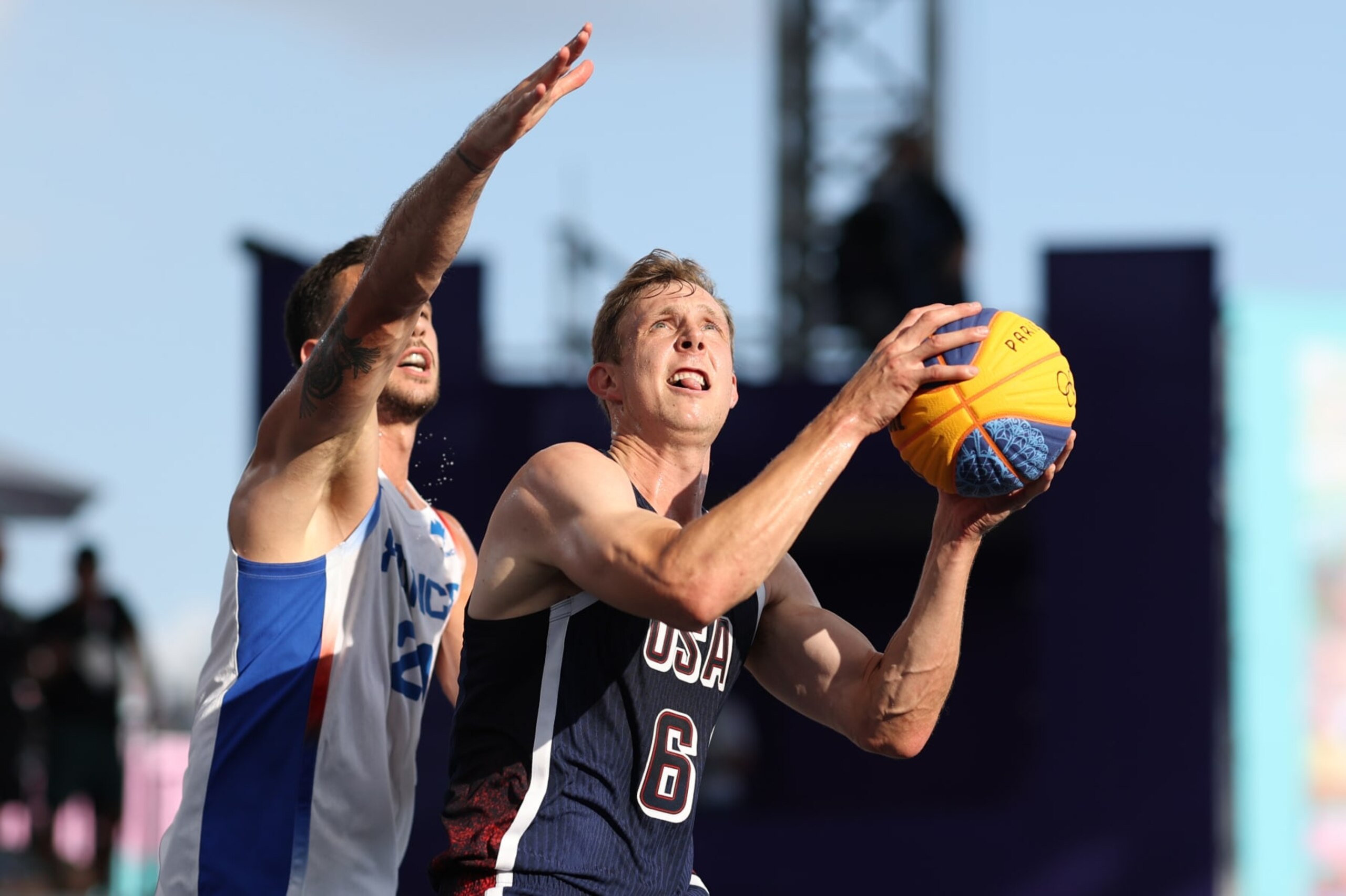 PARIS, FRANCE - AUGUST 02: Canyon Barry #6 of Team United States goes up for a basket past Franck Seguela #21 of Team France during a Men's 3x3 Basketball Pool Round game between the United States and France on day seven of the Olympic Games Paris 2024 at Esplanade Des Invalides on August 02, 2024 in Paris, France. (Photo by Lintao Zhang/Getty Images)