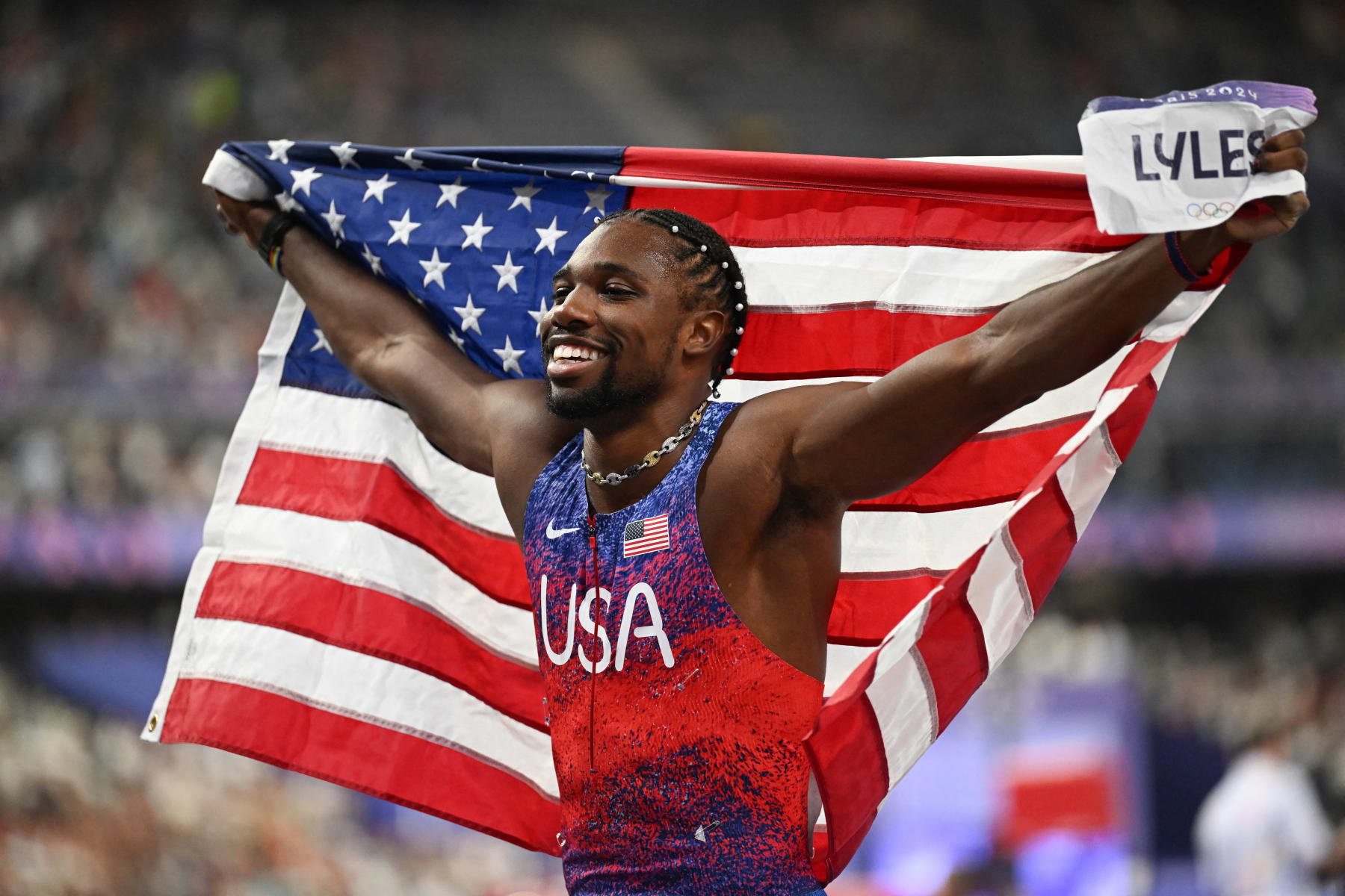 US' Noah Lyles holds a US flag as he celebrates winning the men's 100m final of the athletics event at the Paris 2024 Olympic Games at Stade de France in Saint-Denis, north of Paris, on August 4, 2024. (Photo by MARTIN BERNETTI / AFP) (Photo by MARTIN BERNETTI/AFP via Getty Images)