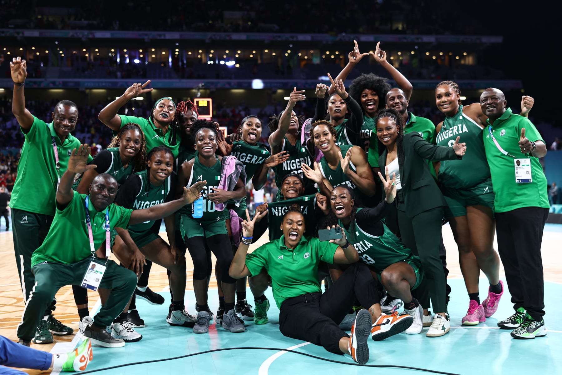 TOPSHOT - Nigeria's players and staff, with Nigeria's US coach Rena Wakama (3rdR) pose as they celebrate after winning the women's preliminary round group B basketball match between Canada and Nigeria during the Paris 2024 Olympic Games at the Pierre-Mauroy stadium in Villeneuve-d'Ascq, northern France, on August 4, 2024. (Photo by Sameer AL-DOUMY / AFP) (Photo by SAMEER AL-DOUMY/AFP via Getty Images)