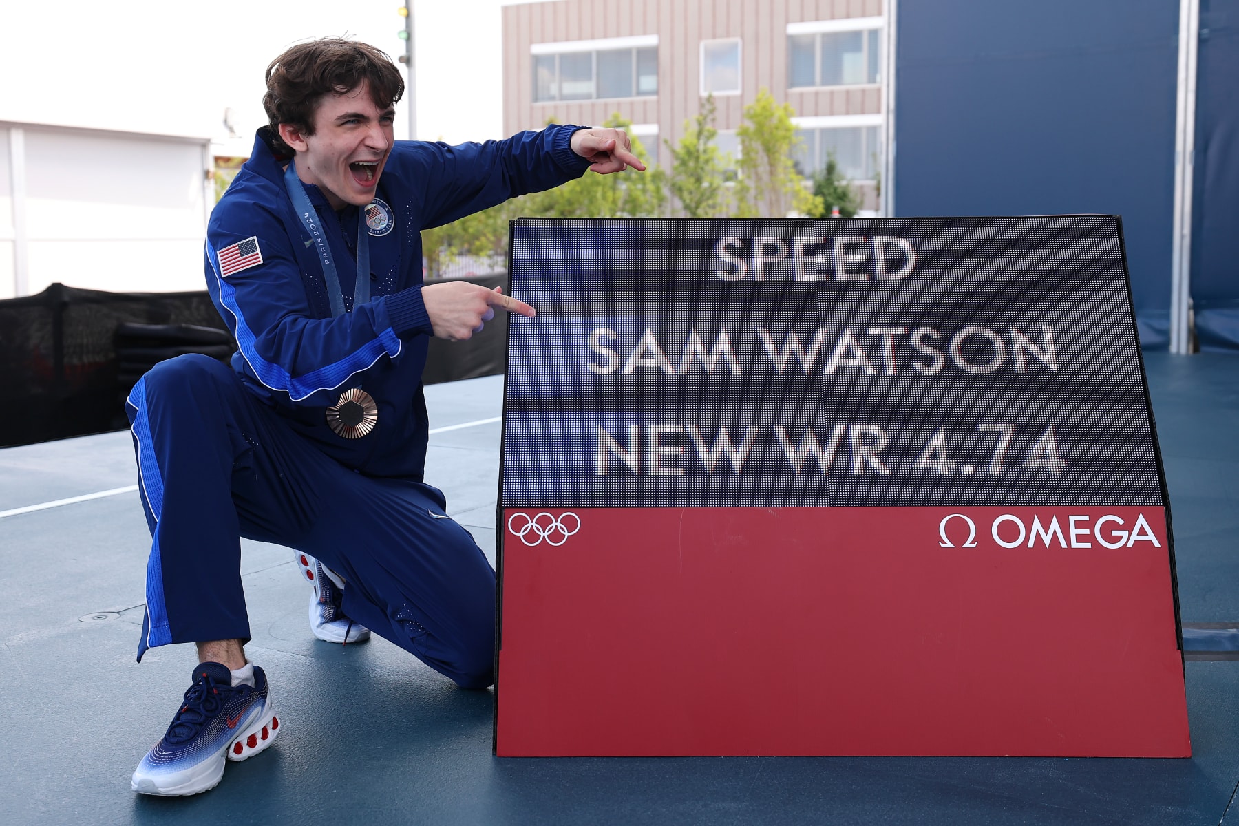 PARIS, FRANCE - AUGUST 08: Bronze medalist Sam Watson of Team United States poses alongside a screen with his world record time of "4.74" during the Sport Climbing medal ceremony after the Men's Speed Big Final on Day thirteen of the Olympic Games Paris 2024 at Le Bourget Sport Climbing Venue on August 08, 2024 in Paris, France. (Photo by Luke Hales/Getty Images)