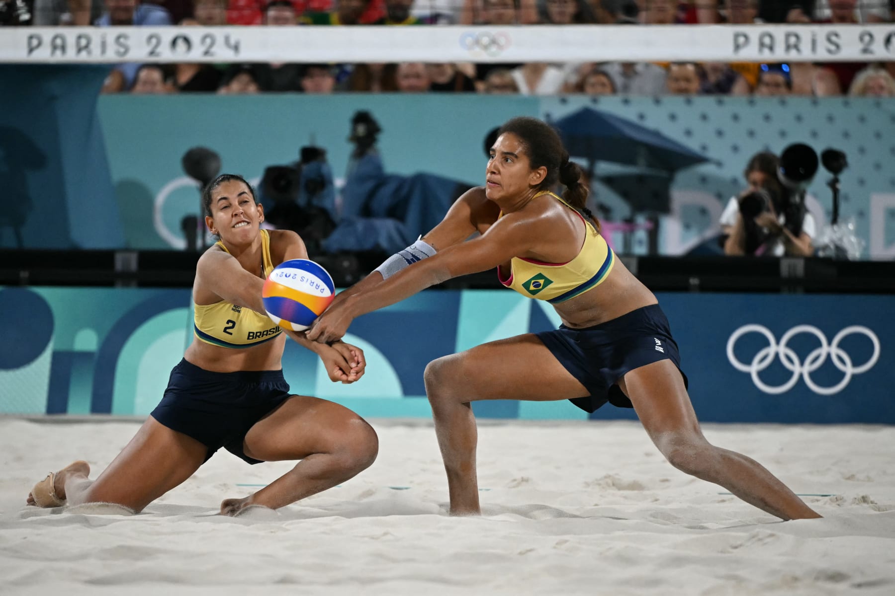 Brazil's #02 Eduarda Santos Lisboa and Brazil's #01 Ana Patricia Silva Ramos reach for the ball in the women's gold medal beach volleyball match between Brazil and Canada during the Paris 2024 Olympic Games at the Eiffel Tower Stadium in Paris on August 9, 2024. (Photo by CARL DE SOUZA / AFP) (Photo by CARL DE SOUZA/AFP via Getty Images)