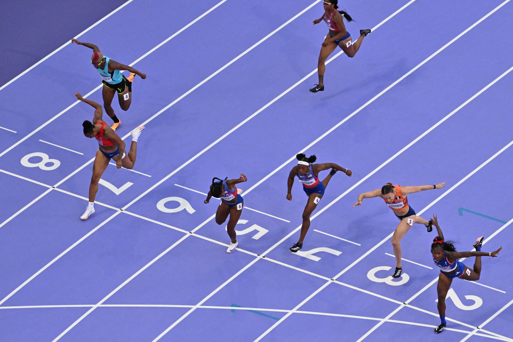 An overview shows US' Masai Russell (5) crossing the finish line ahead of France's Cyrena Samba-Mayela (2) and Puerto Rico's Jasmine Camacho-Quinn (7) in the women's 100m hurdles final of the athletics event at the Paris 2024 Olympic Games at Stade de France in Saint-Denis, north of Paris, on August 10, 2024. (Photo by Antonin THUILLIER / AFP) (Photo by ANTONIN THUILLIER/AFP via Getty Images)