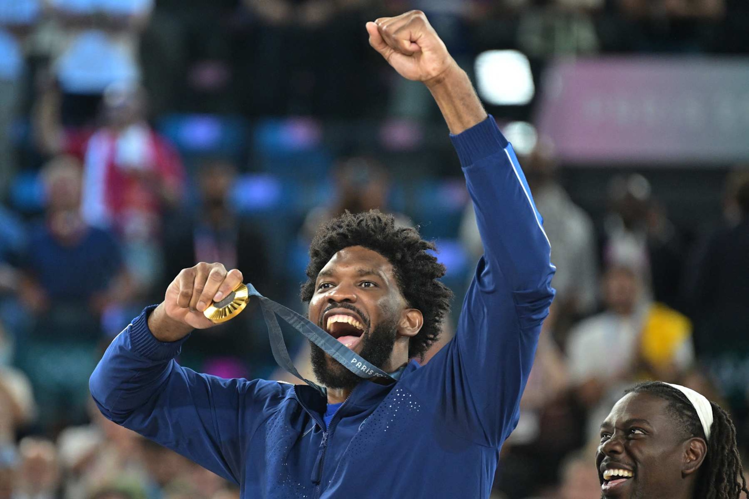 Gold medallist USA's #11 Joel Embiid celebrates on the podium after the men's Gold Medal basketball match between France and USA during the Paris 2024 Olympic Games at the Bercy  Arena in Paris on August 10, 2024. (Photo by Damien MEYER / AFP) (Photo by DAMIEN MEYER/AFP via Getty Images)