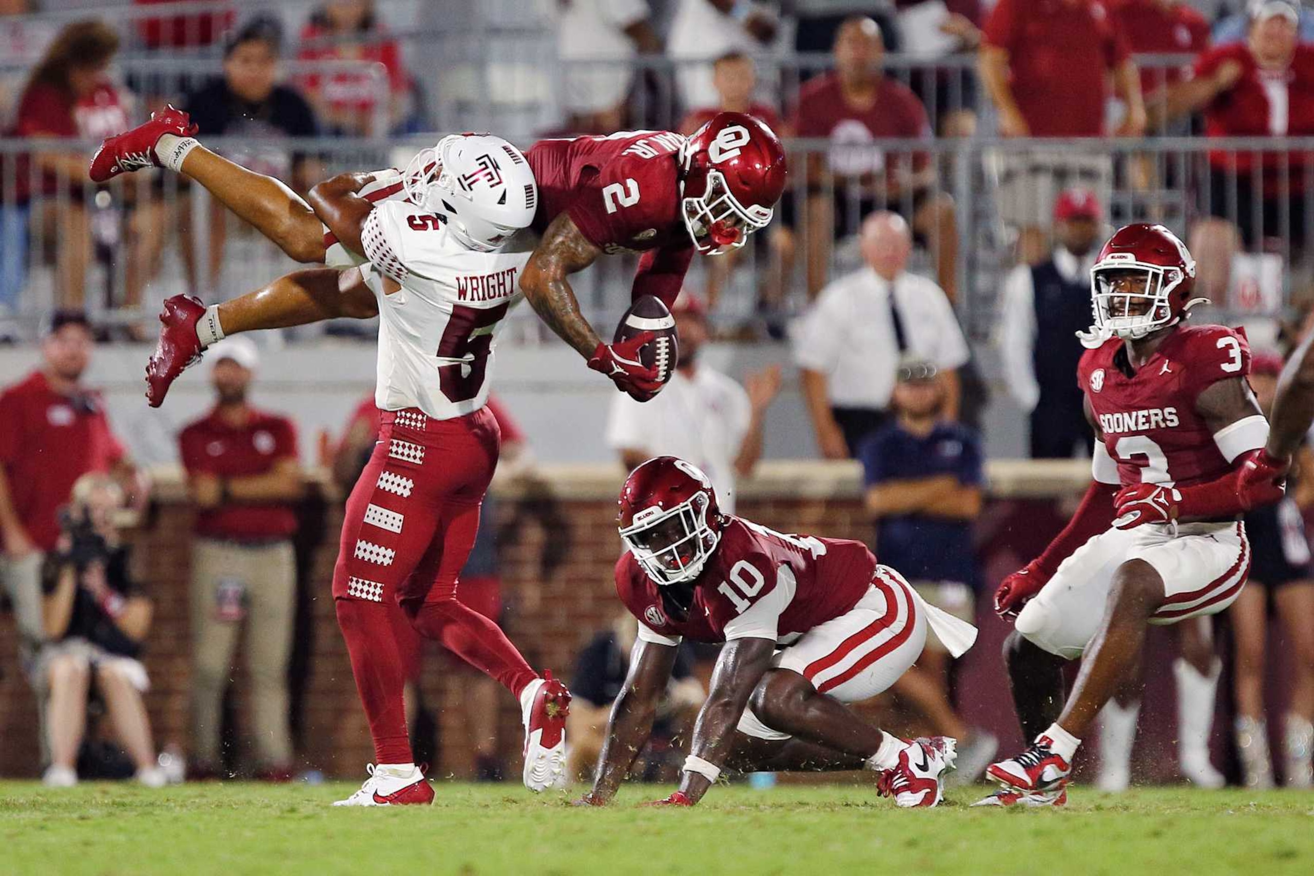 NORMAN, OKLAHOMA - AUGUST 30:  Defensive back Billy Bowman Jr. #2 of the Oklahoma Sooners gets flipped upside down by intended wide receiver Dante Wright #5 of the Temple Owls causing the ball to come loose on the ground in the third quarter at Gaylord Family Oklahoma Memorial Stadium on August 30, 2024 in Norman, Oklahoma.  Oklahoma won 51-3. (Photo by Brian Bahr/Getty Images)