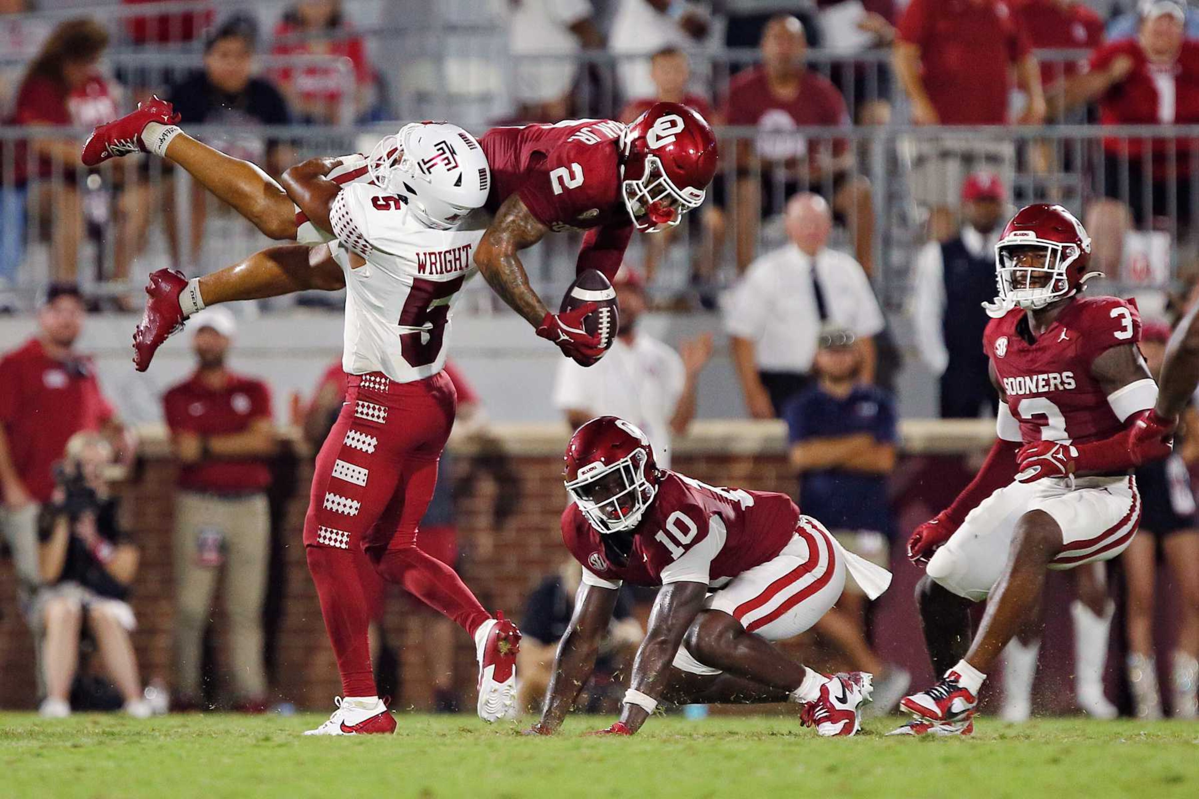 NORMAN, OKLAHOMA - AUGUST 30:  Defensive back Billy Bowman Jr. #2 of the Oklahoma Sooners gets flipped upside down by intended wide receiver Dante Wright #5 of the Temple Owls causing the ball to come loose on the ground in the third quarter at Gaylord Family Oklahoma Memorial Stadium on August 30, 2024 in Norman, Oklahoma.  Oklahoma won 51-3. (Photo by Brian Bahr/Getty Images)