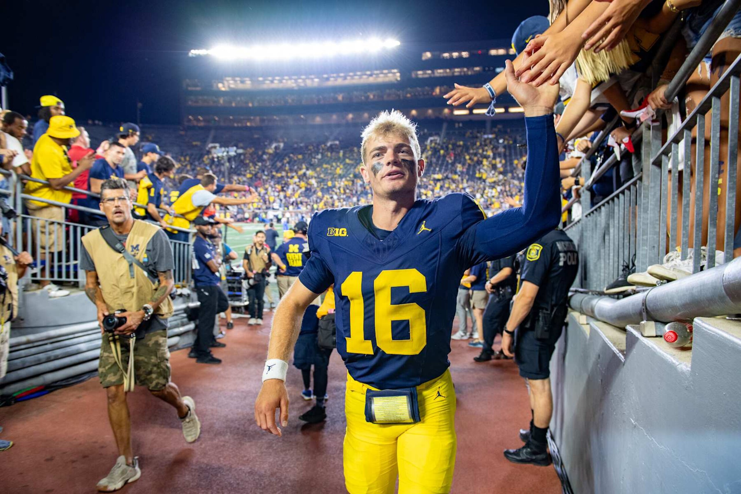 ANN ARBOR, MICHIGAN - AUGUST 31: Davis Warren #16 of the Michigan Wolverines interacts with fans as he walks off the field after a college football game against the Fresno St. Bulldogs at Michigan Stadium on August 31, 2024 in Ann Arbor, Michigan. The Michigan Wolverines won the game 30-10. (Photo by Aaron J. Thornton/Getty Images)