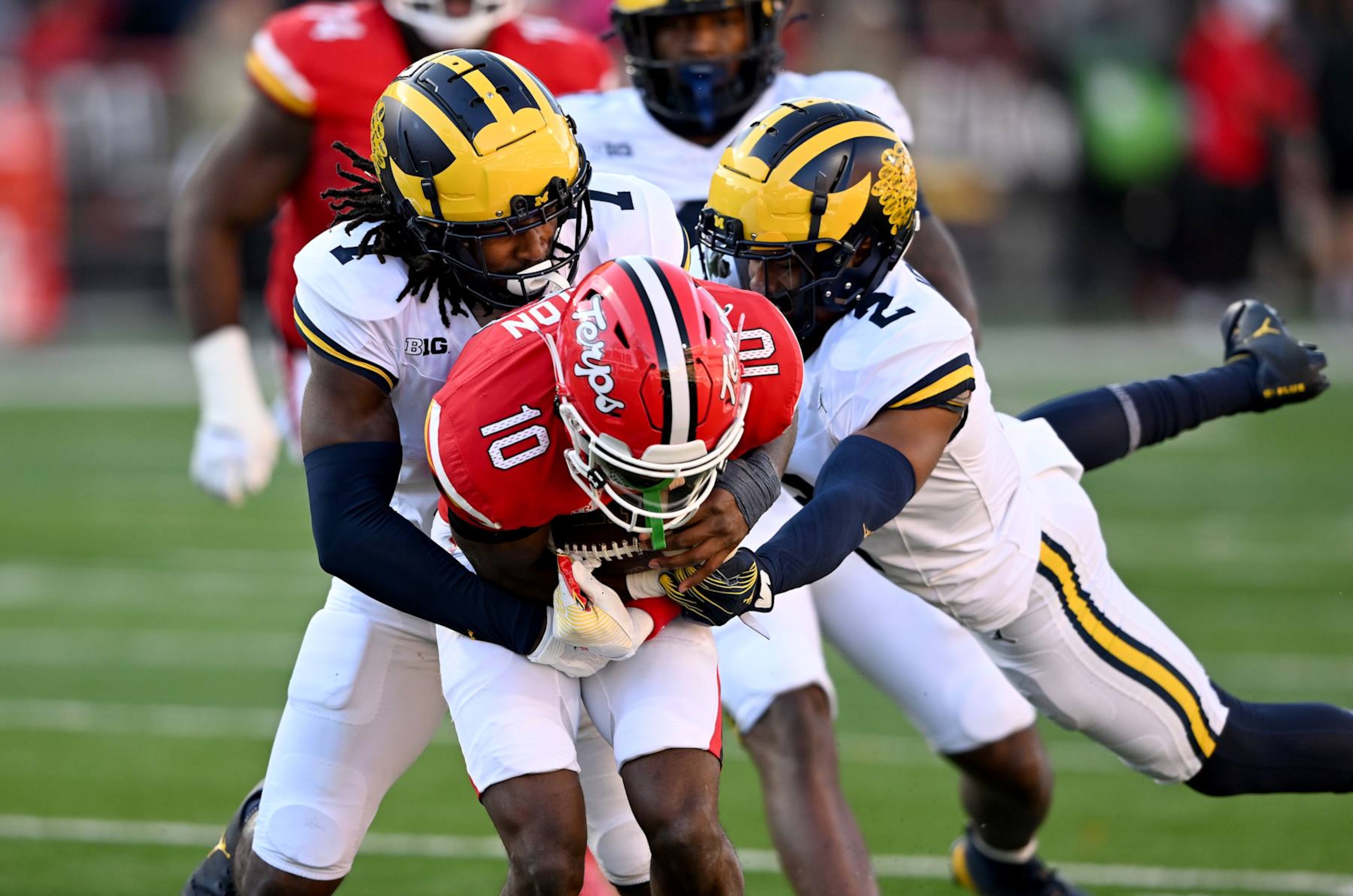 COLLEGE PARK, MARYLAND - NOVEMBER 18: Tai Felton #10 of the Maryland Terrapins is tackled by Makari Paige #7 and Will Johnson #2 of the Michigan Wolverines at SECU Stadium on November 18, 2023 in College Park, Maryland. (Photo by G Fiume/Getty Images)