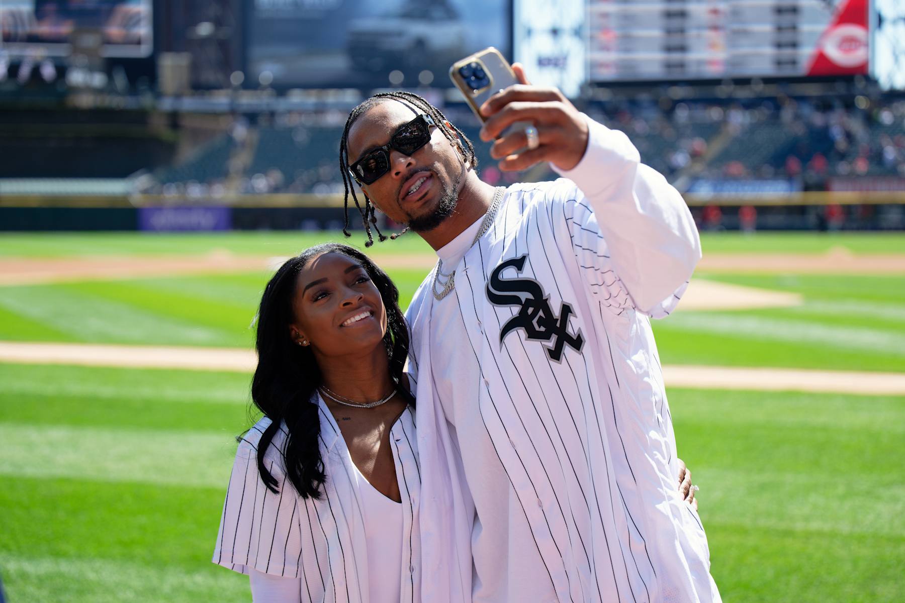 CHICAGO, IL - APRIL 13:  Gymnast Simone Biles and Jonathan Owens of the Chicago Bears record a video on the field before Owens threw out a first pitch before a game between the Cincinnati Reds and the Chicago White Sox at Guaranteed Rate Field on April 13, 2024 in Chicago, Illinois.  (Photo by Jamie Sabau/Getty Images)