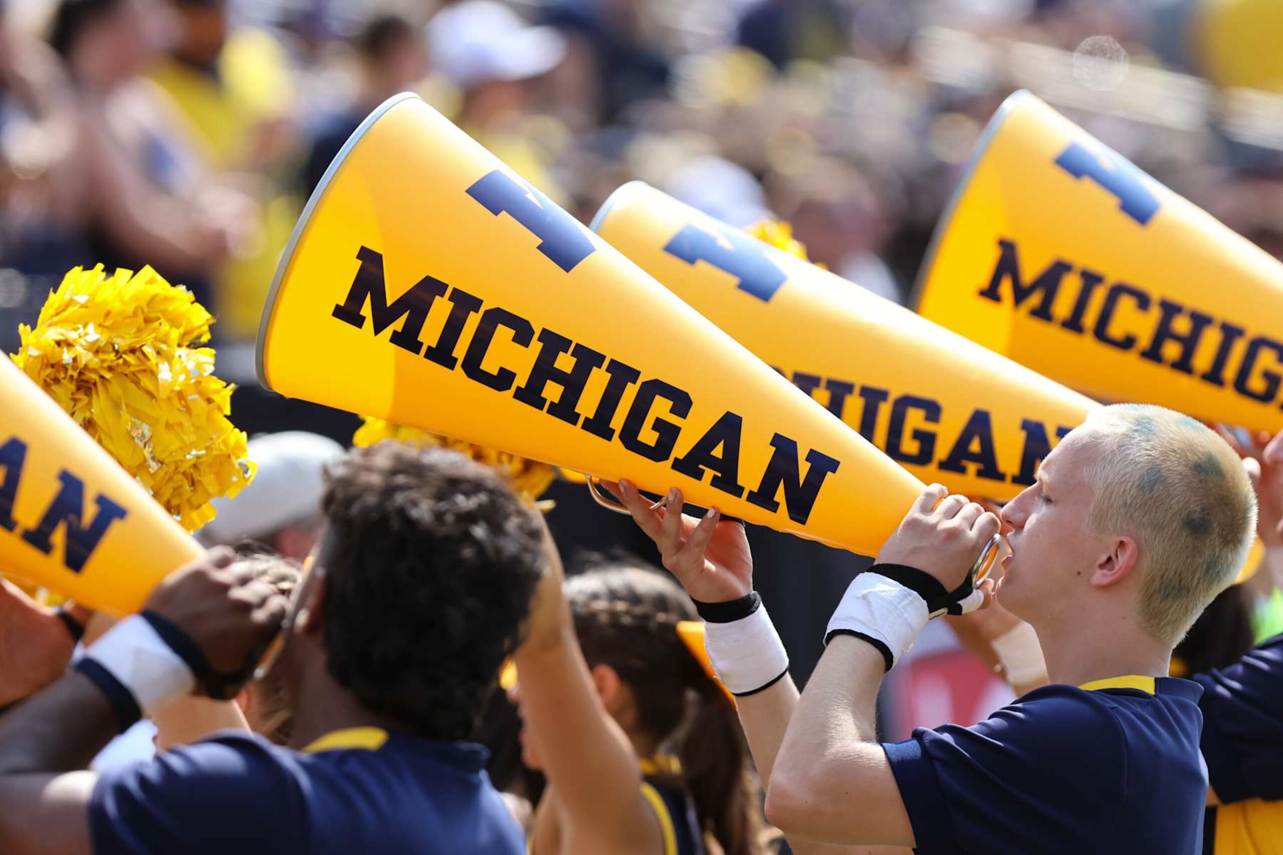 ANN ARBOR, MI - SEPTEMBER 14:  Michigan cheerleaders shout into their megaphones during the second quarter of a non-conference college football game between the Arkansas State Red Wolves and the Michigan Wolverines on September 14, 2024 at Michigan Stadium in Ann Arbor, Michigan.  (Photo by Scott W. Grau/Icon Sportswire via Getty Images)
