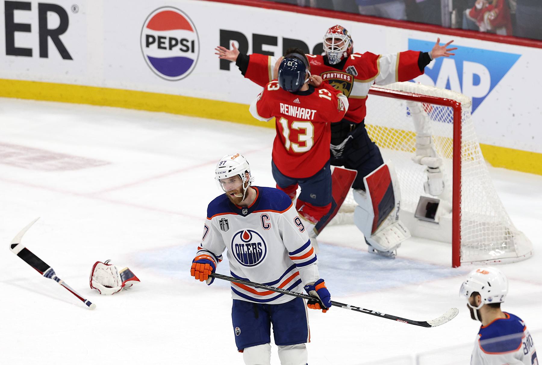 SUNRISE, FLORIDA - JUNE 24: Sergei Bobrovsky #72 and Sam Reinhart #13 of the Florida Panthers celebrate while Connor McDavid #97 of the Edmonton Oilers looks on after Florida's 2-1 victory in Game Seven of the 2024 Stanley Cup Final at Amerant Bank Arena on June 24, 2024 in Sunrise, Florida. (Photo by Elsa/Getty Images)