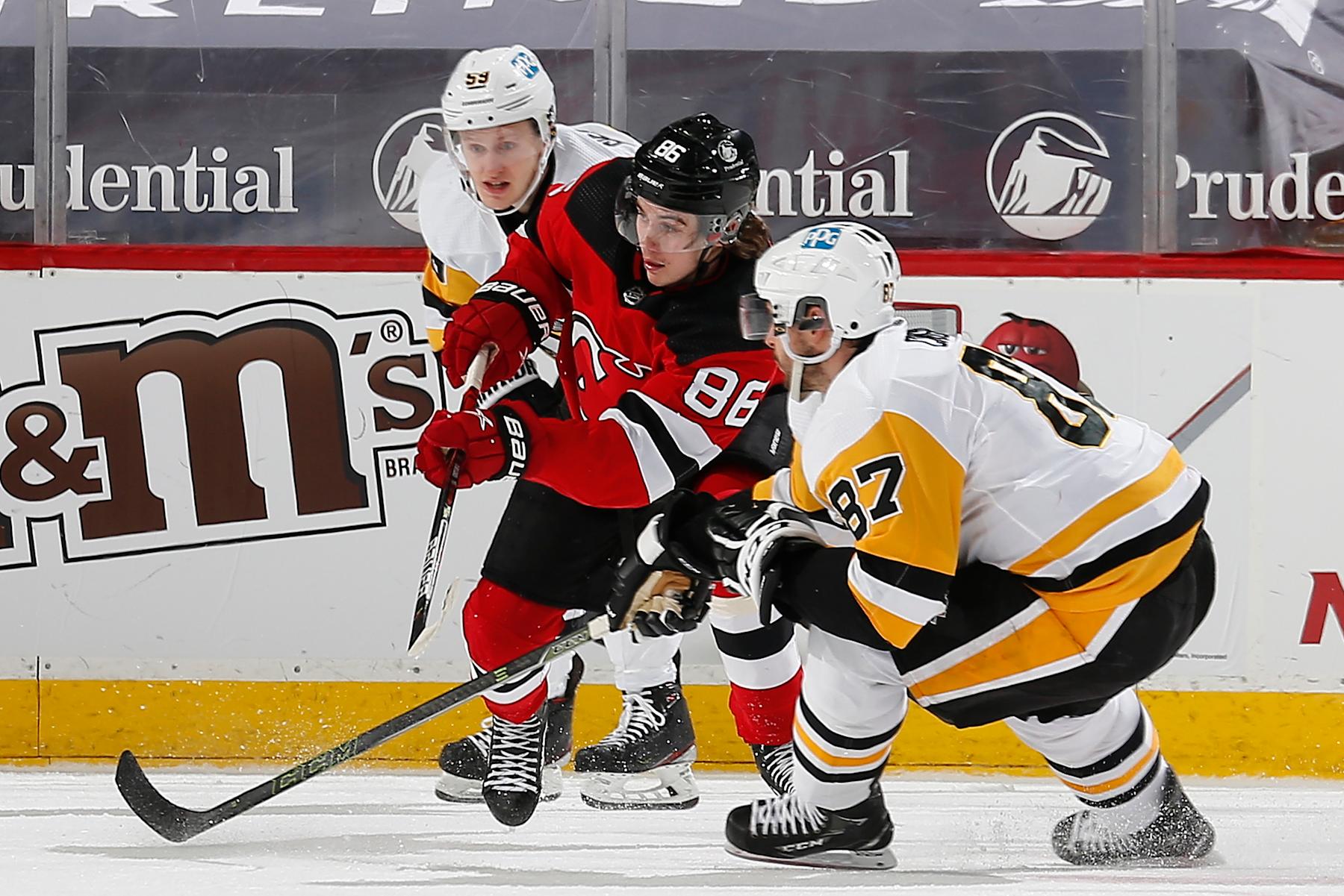 NEWARK, NEW JERSEY - APRIL 11: Jack Hughes #86 of the New Jersey Devils is defended by Jake Guentzel #59 and Sidney Crosby #87 of the Pittsburgh Penguins during the first period at Prudential Center on April 11, 2021 in Newark, New Jersey. (Photo by Andy Marlin/NHLI via Getty Images)