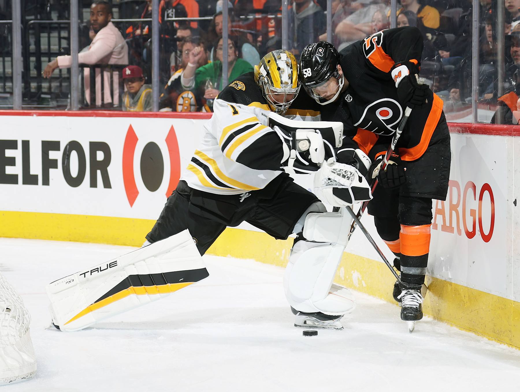 PHILADELPHIA, PENNSYLVANIA - APRIL 09: Jeremy Swayman #1 of the Boston Bruins attempts to play the puck behind his net against Tanner Laczynski #58 of the Philadelphia Flyers at the Wells Fargo Center on April 9, 2023 in Philadelphia, Pennsylvania. The Bruins went on to defeat the Flyers 5-3. The win was the Bruins' 63rd of the season, which is a new NHL record for wins in a single regular season. (Photo by Len Redkoles/NHLI via Getty Images)