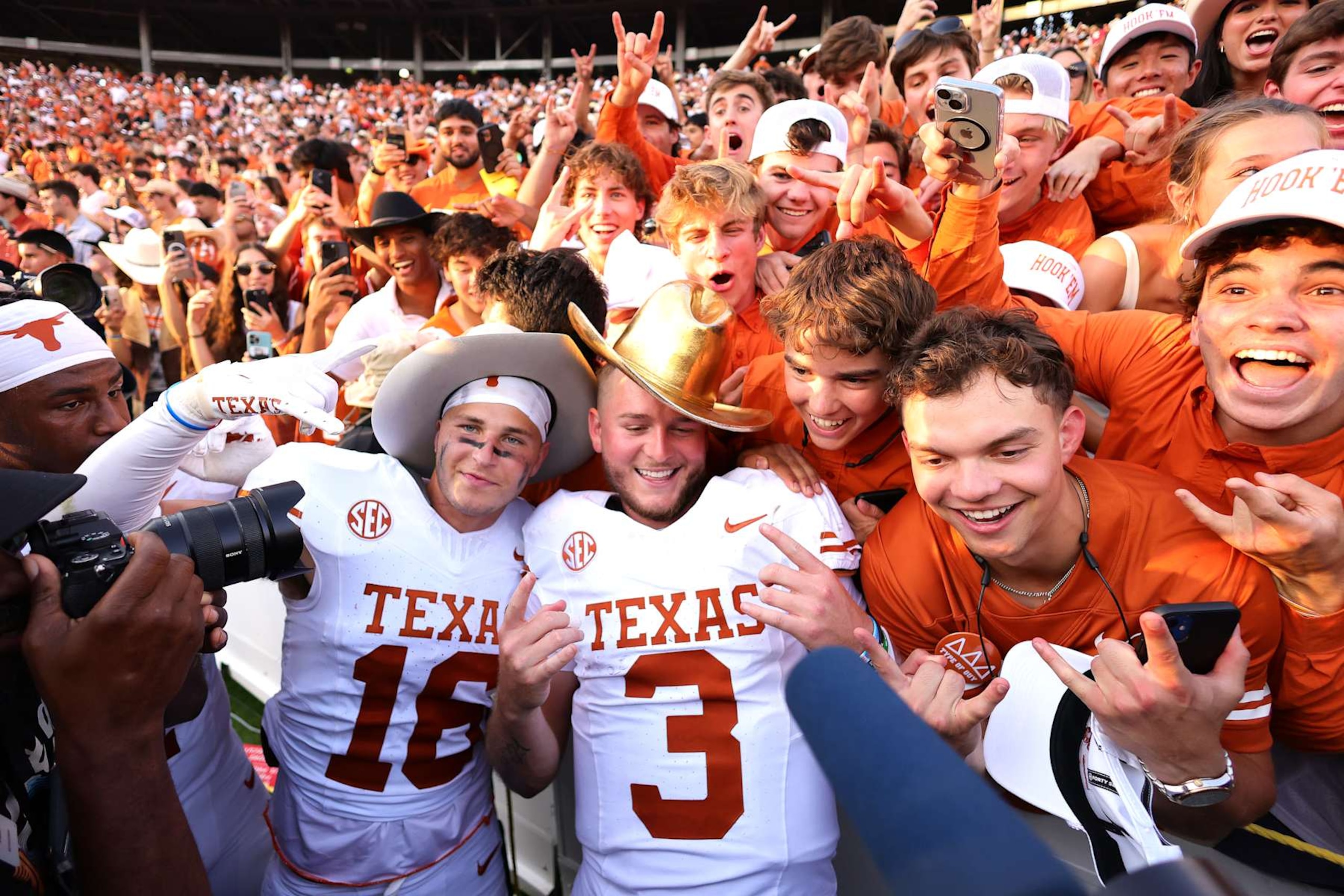 DALLAS, TEXAS - OCTOBER 12: Quinn Ewers #3 of the Texas Longhorns poses with fans and teammates while wearing the Golden Hat Trophy after defeating the Oklahoma Sooners 34 at Cotton Bowl Stadium on October 12, 2024 in Dallas, Texas. (Photo by Alex Slitz/Getty Images)