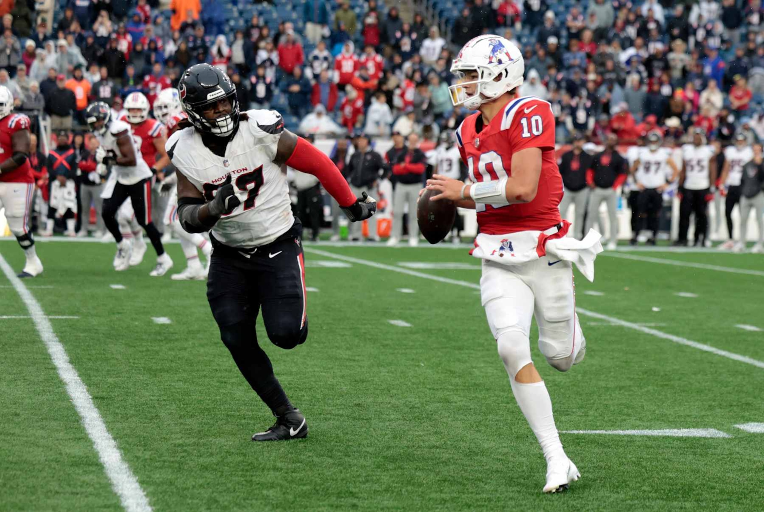 FOXBOROUGH, MA - OCTOBER 13: New England Patriots quarterback Drake Maye (10) chased form the pocket by Houston Texans defensive tackle Mario Edwards Jr.  (97) during a game between the New England Patriots and the Houston Texans on October 13, 2024, at Gillette Stadium in Foxborough, Massachusetts. (Photo by Fred Kfoury III/Icon Sportswire via Getty Images)