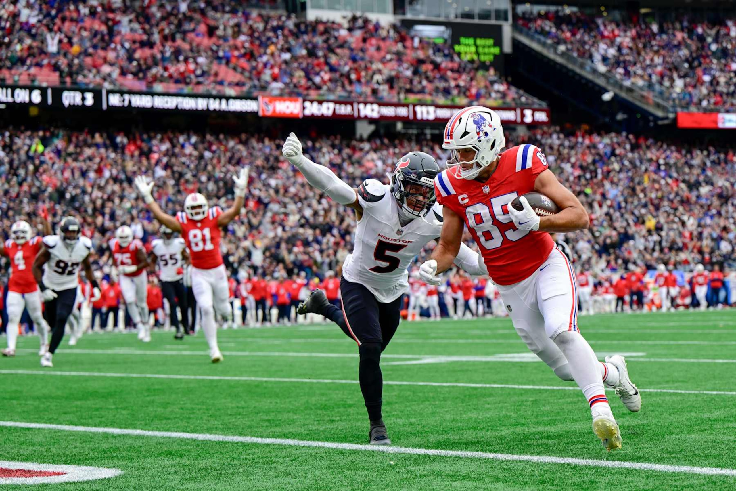 FOXBOROUGH, MASSACHUSETTS - OCTOBER 13: Hunter Henry #85 of the New England Patriots carries the ball for a touchdown against Jalen Pitre #5 of the Houston Texans during the third quarter at Gillette Stadium on October 13, 2024 in Foxborough, Massachusetts. (Photo by Maddie Malhotra/Getty Images)