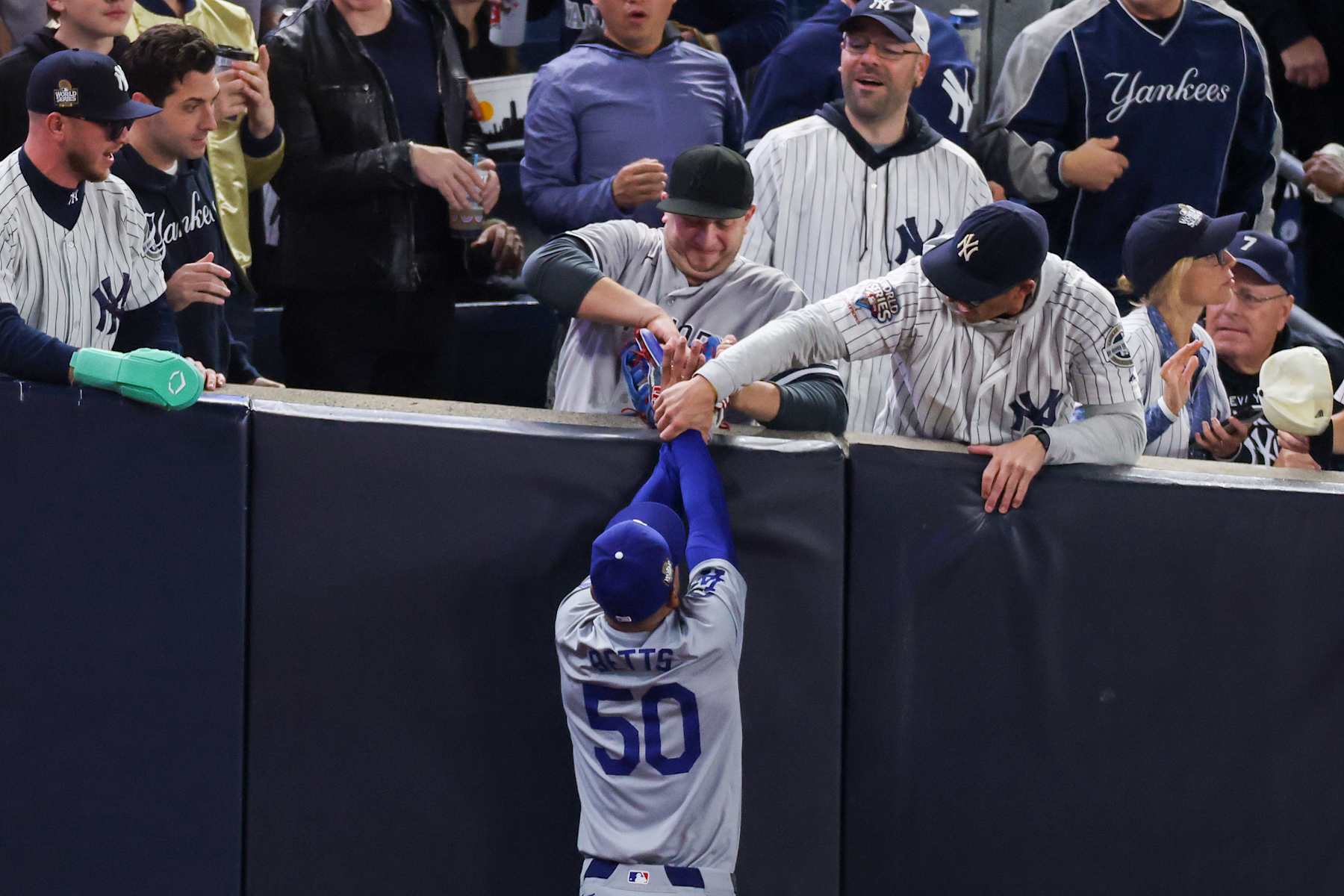 NEW YORK, NEW YORK - OCTOBER 29: Fans interfere with Mookie Betts #50 of the Los Angeles Dodgers as he attempts to catch a fly ball in foul territory during the first inning of Game Four of the 2024 World Series against the New York Yankees at Yankee Stadium on October 29, 2024 in the Bronx borough of New York City. The play resulted in an out. (Photo by Al Bello/Getty Images)