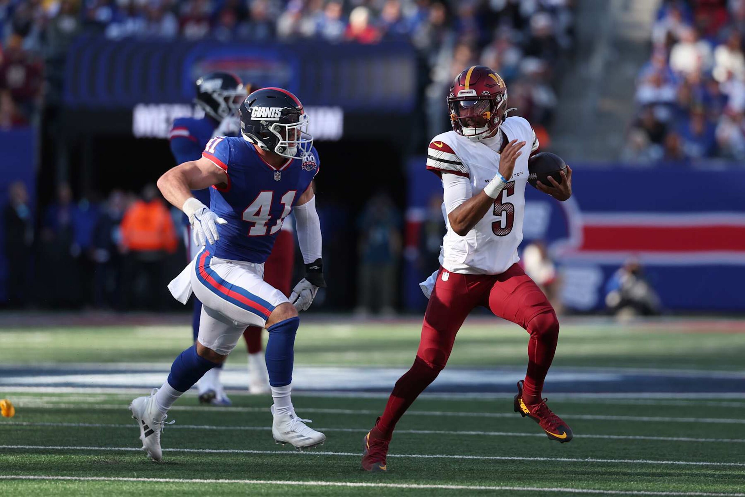 EAST RUTHERFORD, NEW JERSEY - NOVEMBER 03: Jayden Daniels #5 of the Washington Commanders is chased by Micah McFadden #41 of the New York Giants during the first half at MetLife Stadium on November 03, 2024 in East Rutherford, New Jersey. (Photo by Al Bello/Getty Images)