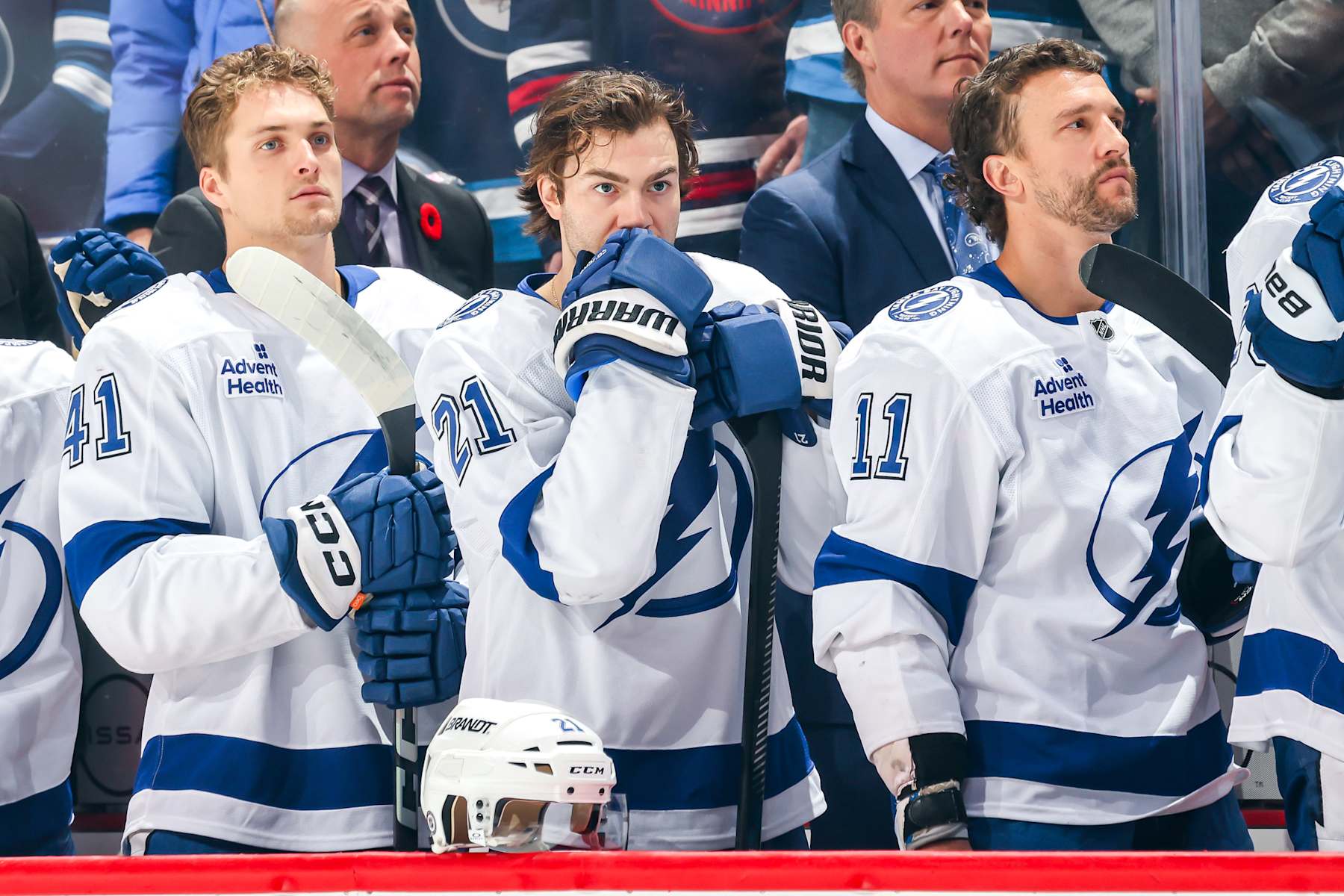 WINNIPEG, CANADA - NOVEMBER 3: Mitchell Chaffee #41, Brayden Point #21 and Luke Glendening #11 of the Tampa Bay Lightning stand on the bench during the singing of the National anthems prior to puck drop against the Winnipeg Jets at the Canada Life Centre on November 3, 2024 in Winnipeg, Manitoba, Canada. (Photo by Jonathan Kozub/NHLI via Getty Images)