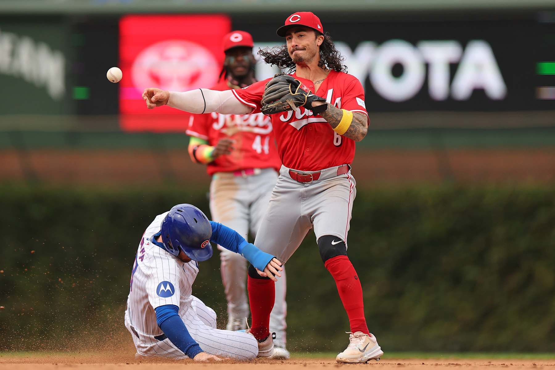 CHICAGO, ILLINOIS - SEPTEMBER 27: Jonathan India #6 of the Cincinnati Reds turns a double play past a sliding Ian Happ #8 of the Chicago Cubs during the seventh inning at Wrigley Field on September 27, 2024 in Chicago, Illinois. (Photo by Michael Reaves/Getty Images)