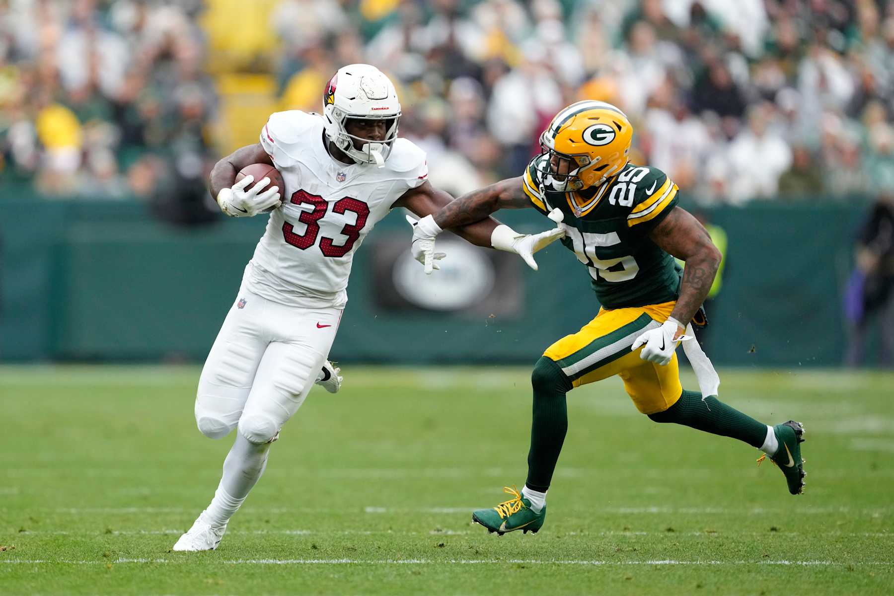 GREEN BAY, WISCONSIN - OCTOBER 13: Trey Benson #33 of the Arizona Cardinals runs with the ball against Keisean Nixon #25 of the Green Bay Packers in the second half at Lambeau Field on October 13, 2024 in Green Bay, Wisconsin. (Photo by Patrick McDermott/Getty Images)
