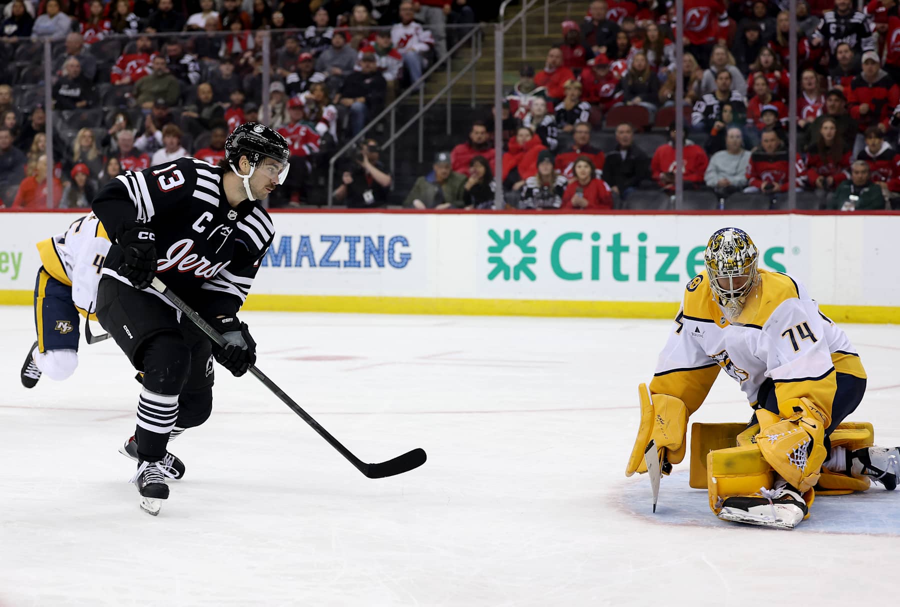 NEWARK, NEW JERSEY - NOVEMBER 25: Nico Hischier #13 of the New Jersey Devils scores his third goal of the game as Juuse Saros #74 of the Nashville Predators defends during the second period at Prudential Center on November 25, 2024 in Newark, New Jersey. (Photo by Elsa/Getty Images)