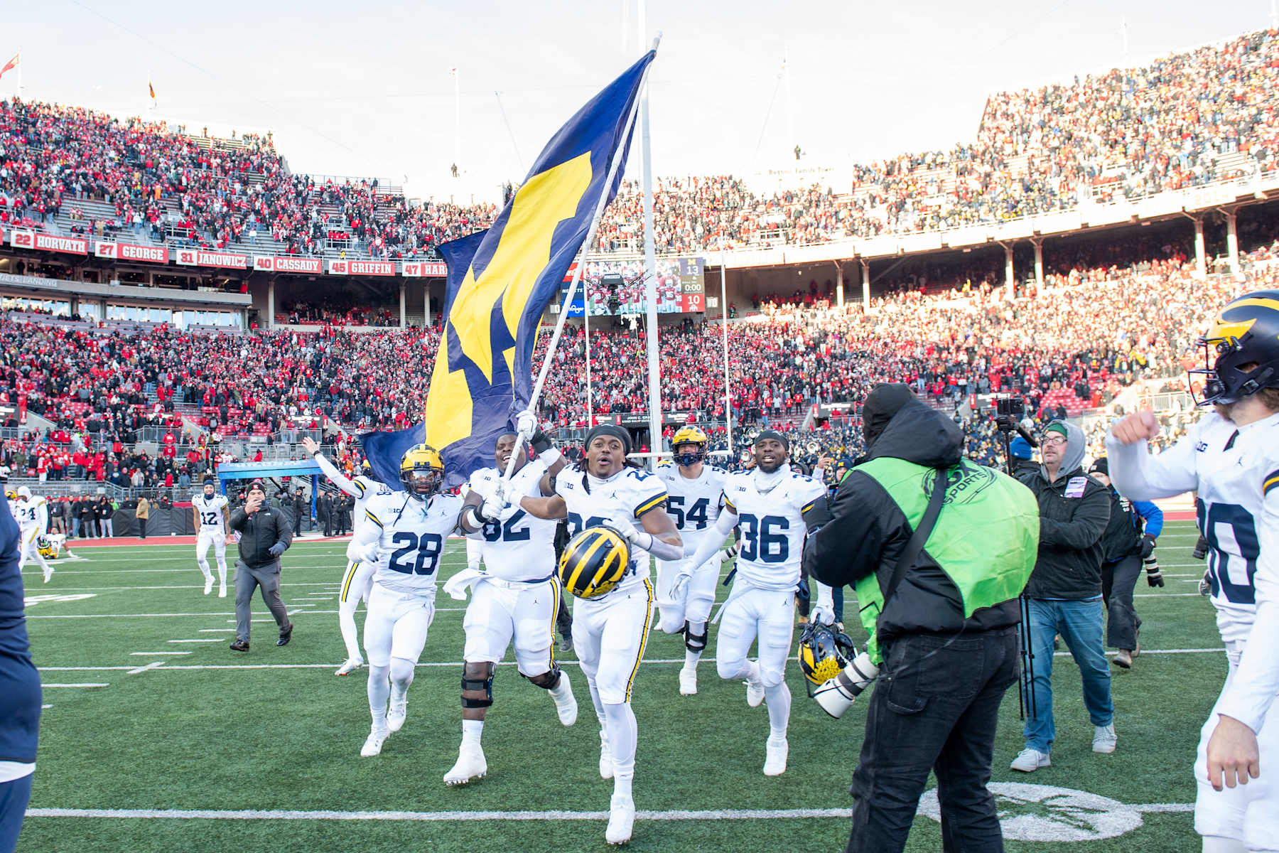 COLUMBUS, OHIO - NOVEMBER 30: Quinton Johnson #28, Raheem Anderson #62, Tavierre Dunlap #22, and Keshaun Harris #36 of the Michigan Wolverines run to plant the Michigan flag at center field after a college football game against the Ohio State Buckeyes at Ohio Stadium on November 30, 2024 in Columbus, OH. The Michigan Wolverines won the game 13-10. (Photo by Aaron J. Thornton/Getty Images)