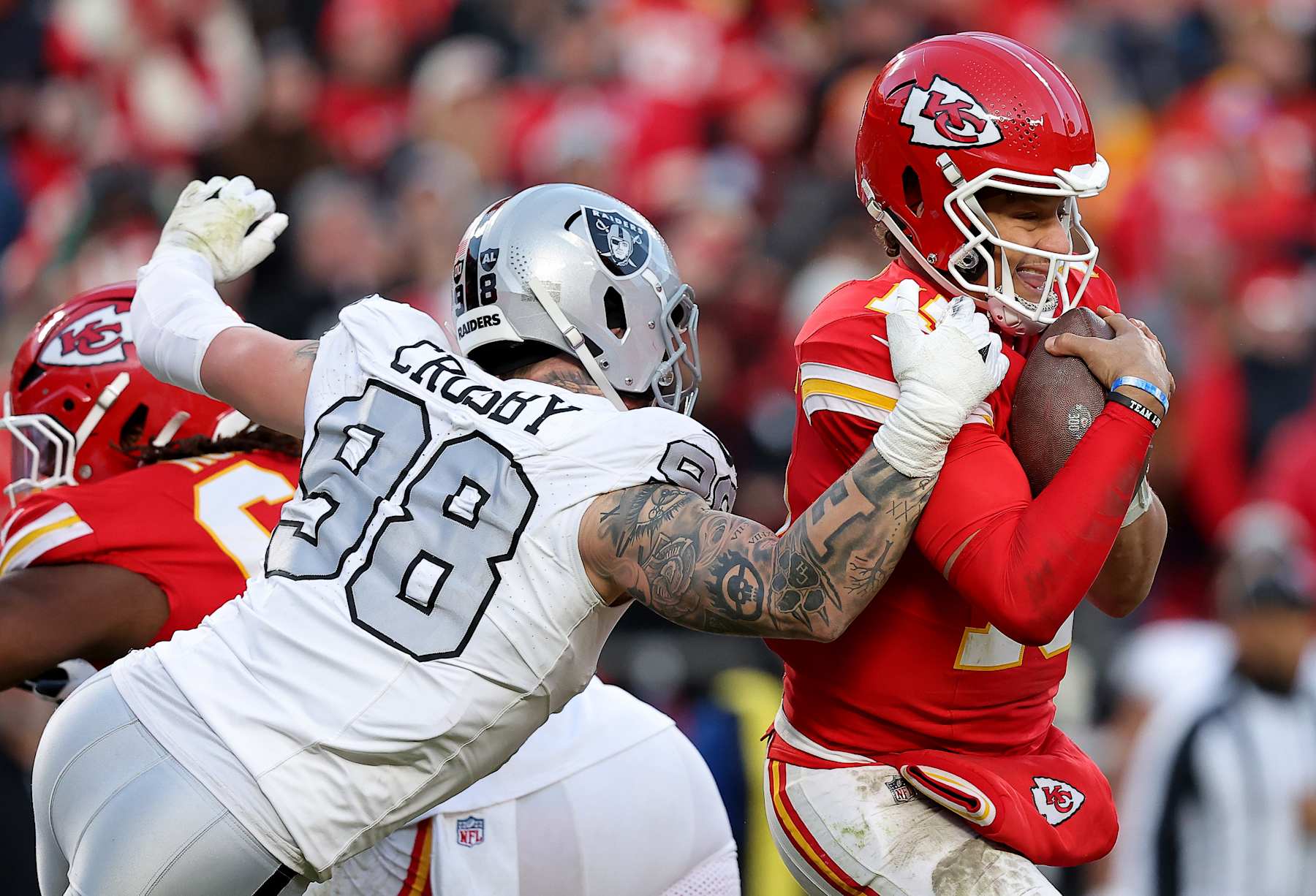 KANSAS CITY, MISSOURI - NOVEMBER 29: Patrick Mahomes #15 of the Kansas City Chiefs escapes a sack against Maxx Crosby #98 of the Las Vegas Raiders during the third quarter in the game at GEHA Field at Arrowhead Stadium on November 29, 2024 in Kansas City, Missouri. (Photo by David Eulitt/Getty Images)