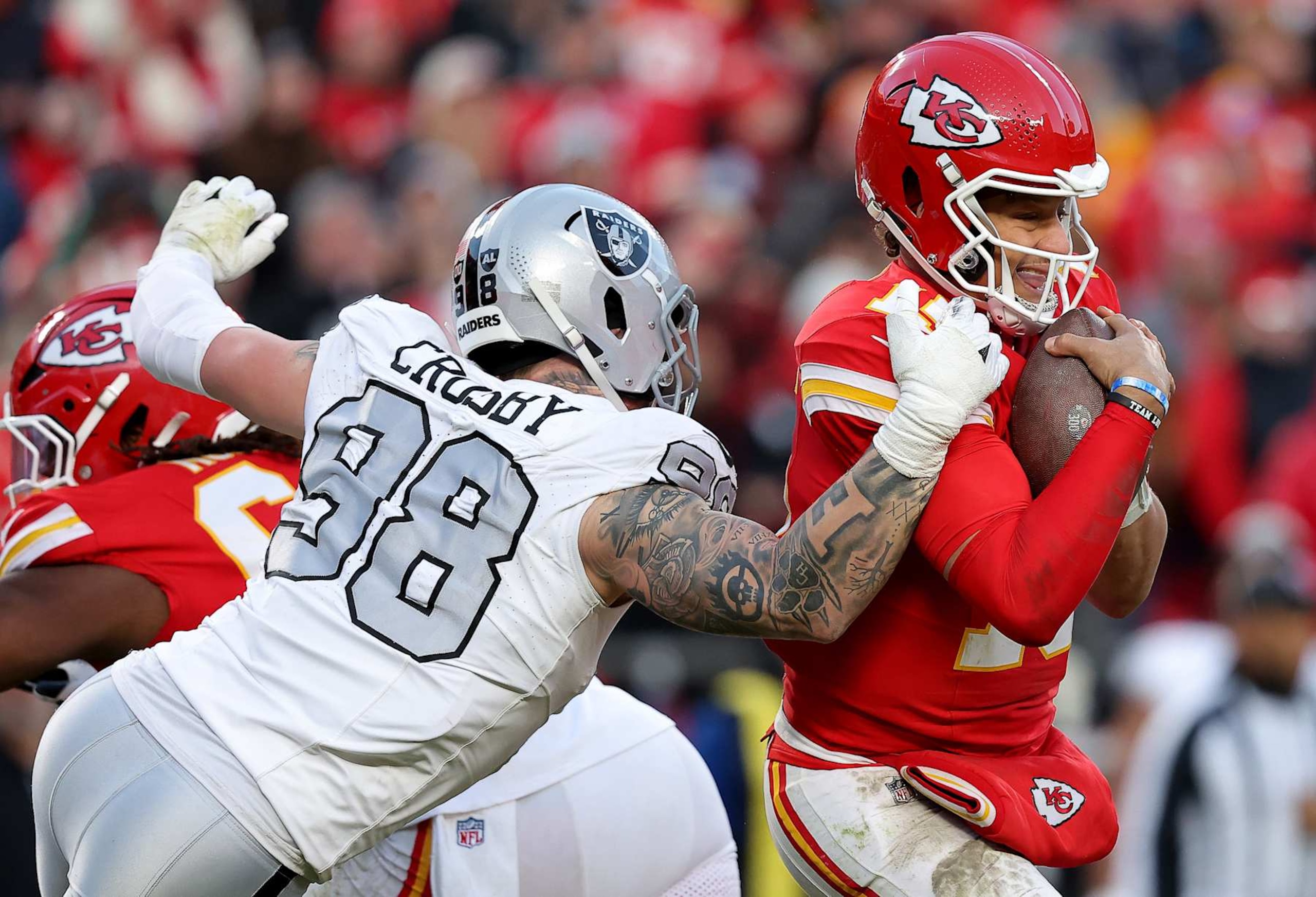 KANSAS CITY, MISSOURI - NOVEMBER 29: Patrick Mahomes #15 of the Kansas City Chiefs escapes a sack against Maxx Crosby #98 of the Las Vegas Raiders during the third quarter in the game at GEHA Field at Arrowhead Stadium on November 29, 2024 in Kansas City, Missouri. (Photo by David Eulitt/Getty Images)