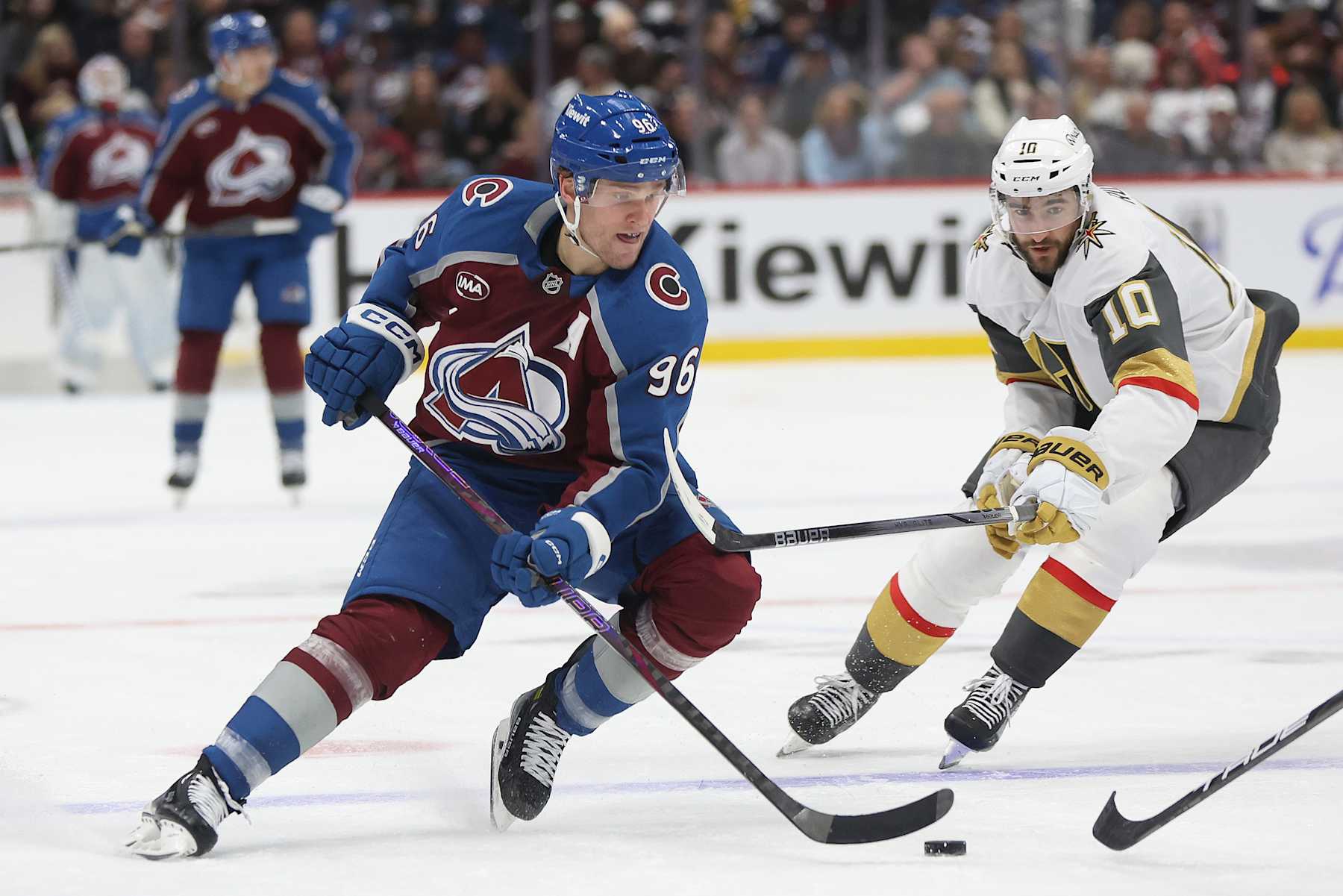DENVER, COLORADO - NOVEMBER 27: Mikko Rantanen #96 of the Colorado Avalanche advances the puck against Nicolas Roy #10 of the Vegas Golden Knights in the second period at Ball Arena on November 27, 2024 in Denver, Colorado. (Photo by Matthew Stockman/Getty Images)