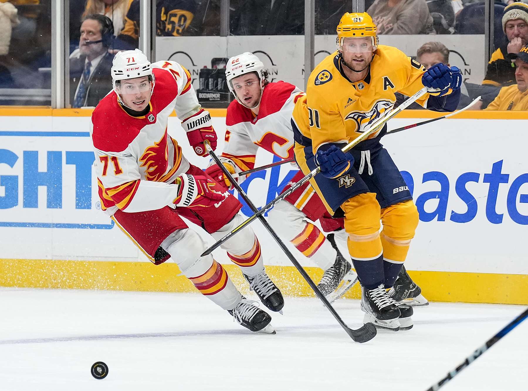 NASHVILLE, TENNESSEE - DECEMBER 10: Walker Duehr #71 of the Calgary Flames skates against Steven Stamkos #91 of the Nashville Predators during an NHL game at Bridgestone Arena on December 10, 2024 in Nashville, Tennessee. (Photo by John Russell/NHLI via Getty Images)